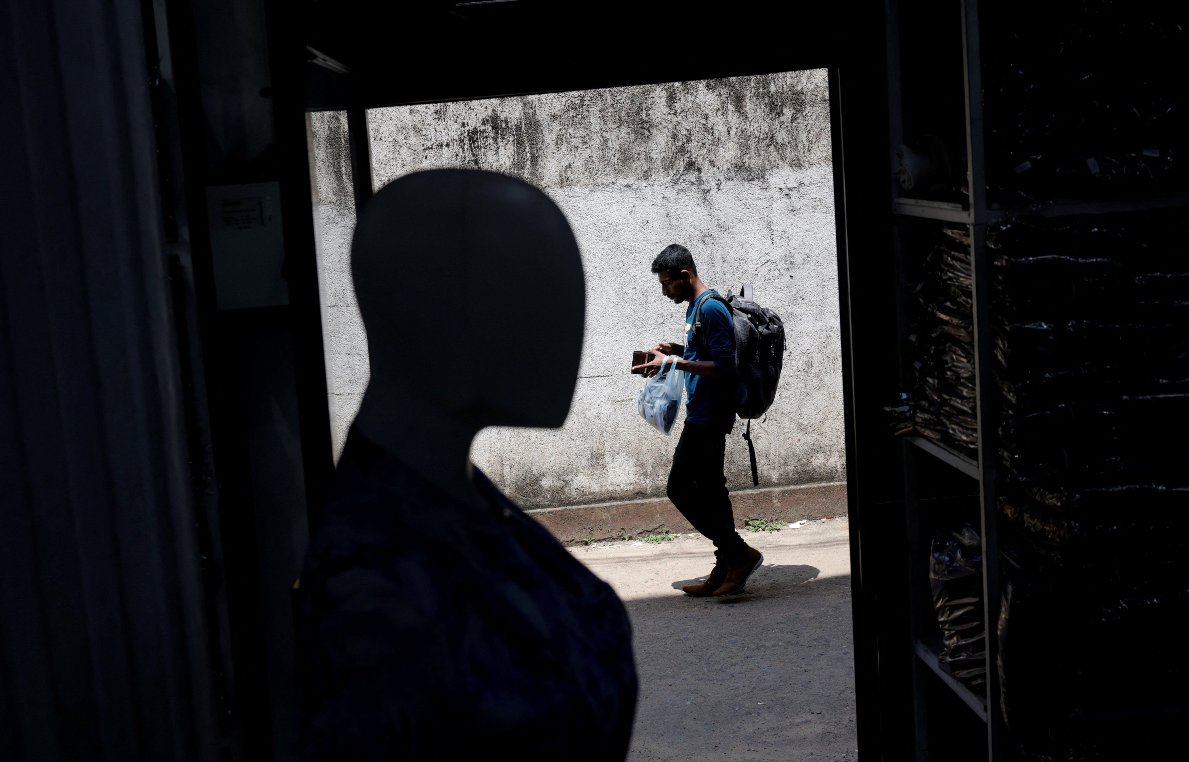 A man walks past a wholesale clothes shop while checking his wallet in Colombo, Sri Lanka, on April 11. Sri Lanka is geopolitically more relevant to China than many other debt-ridden countries. Photo: Reuters