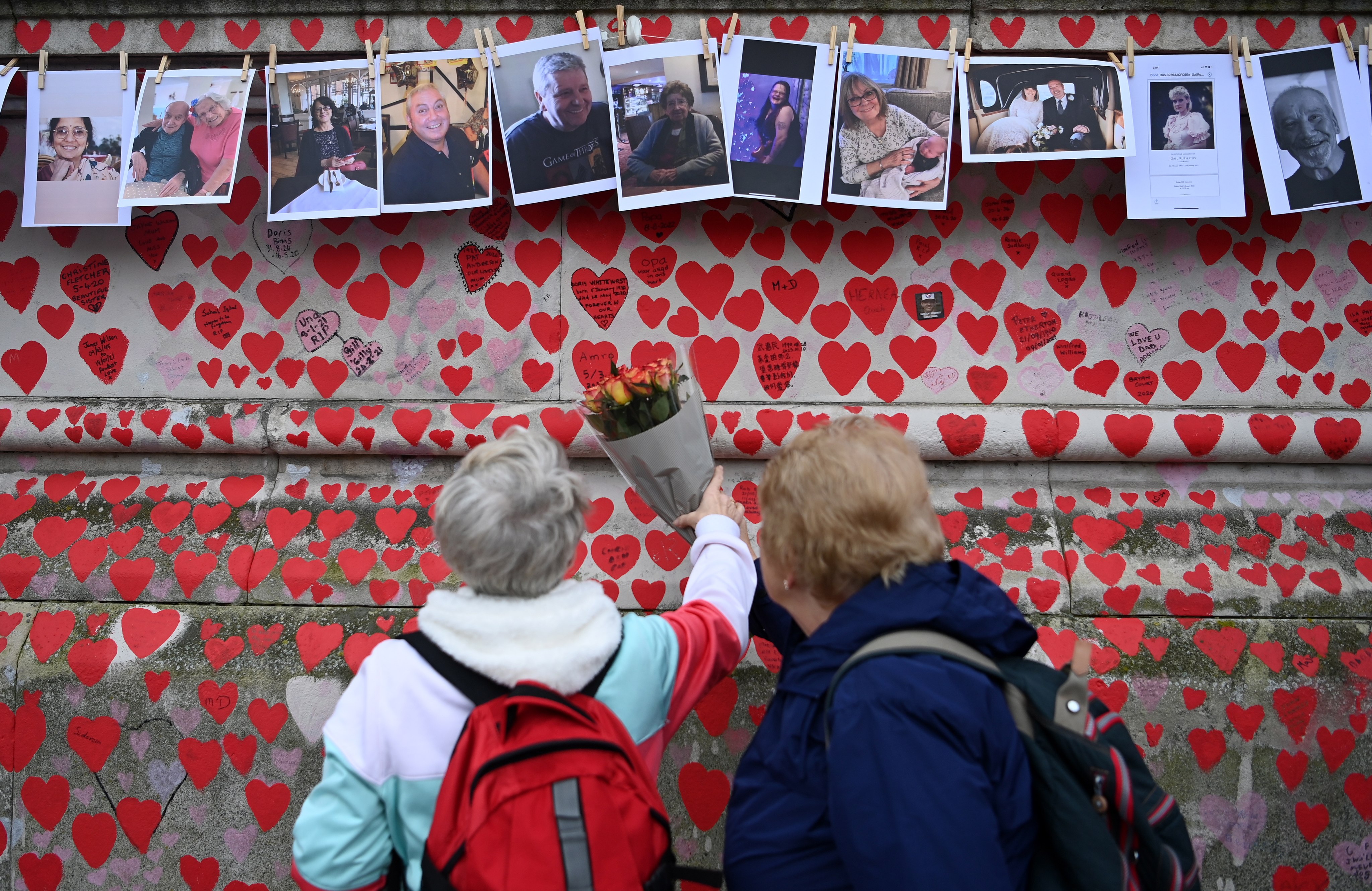 Bereaved families look at photographs of the dead on the Covid Memorial Wall in London, Britain. Photo: EPA-EFE