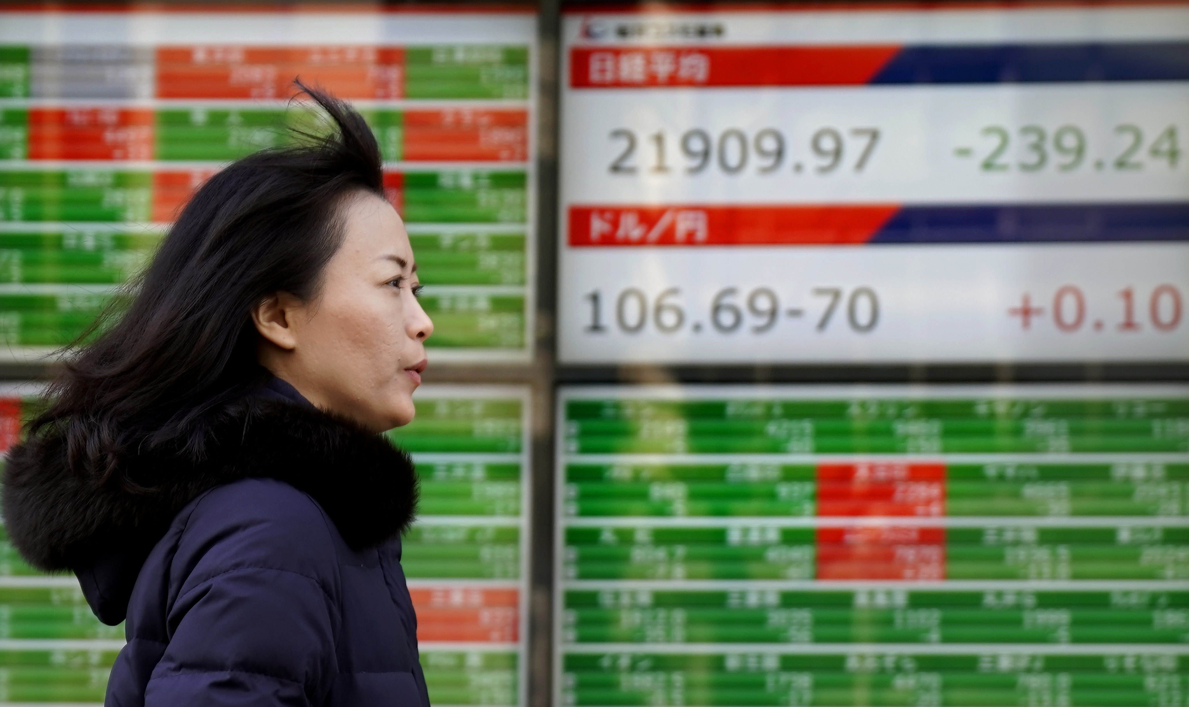 A woman walks past an electronic stock indicator in Tokyo, Japan. File photo: AP