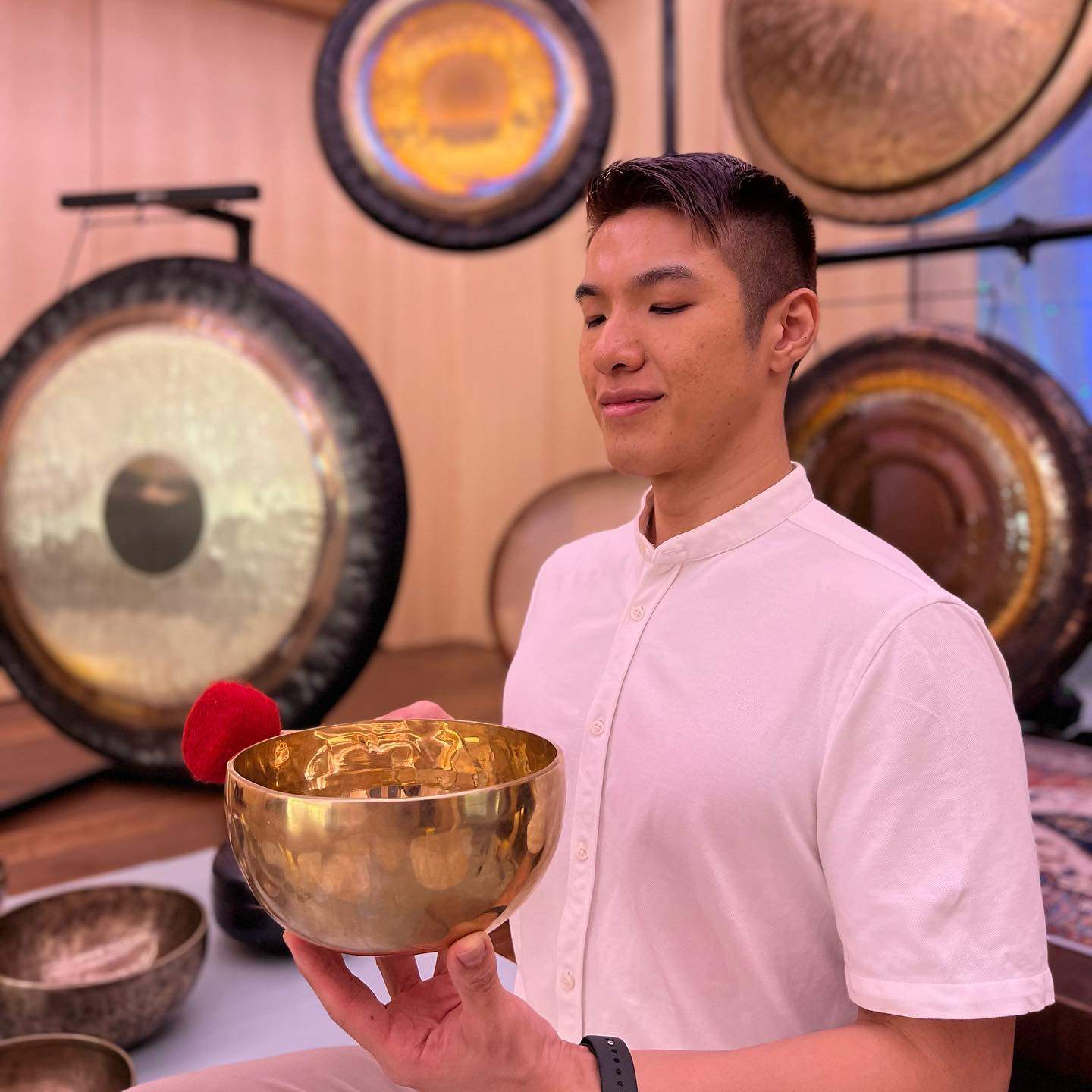 Malbert Lee, surrounded by gongs,  holds a singing bowl. Photo: Instagram/@malbertlee