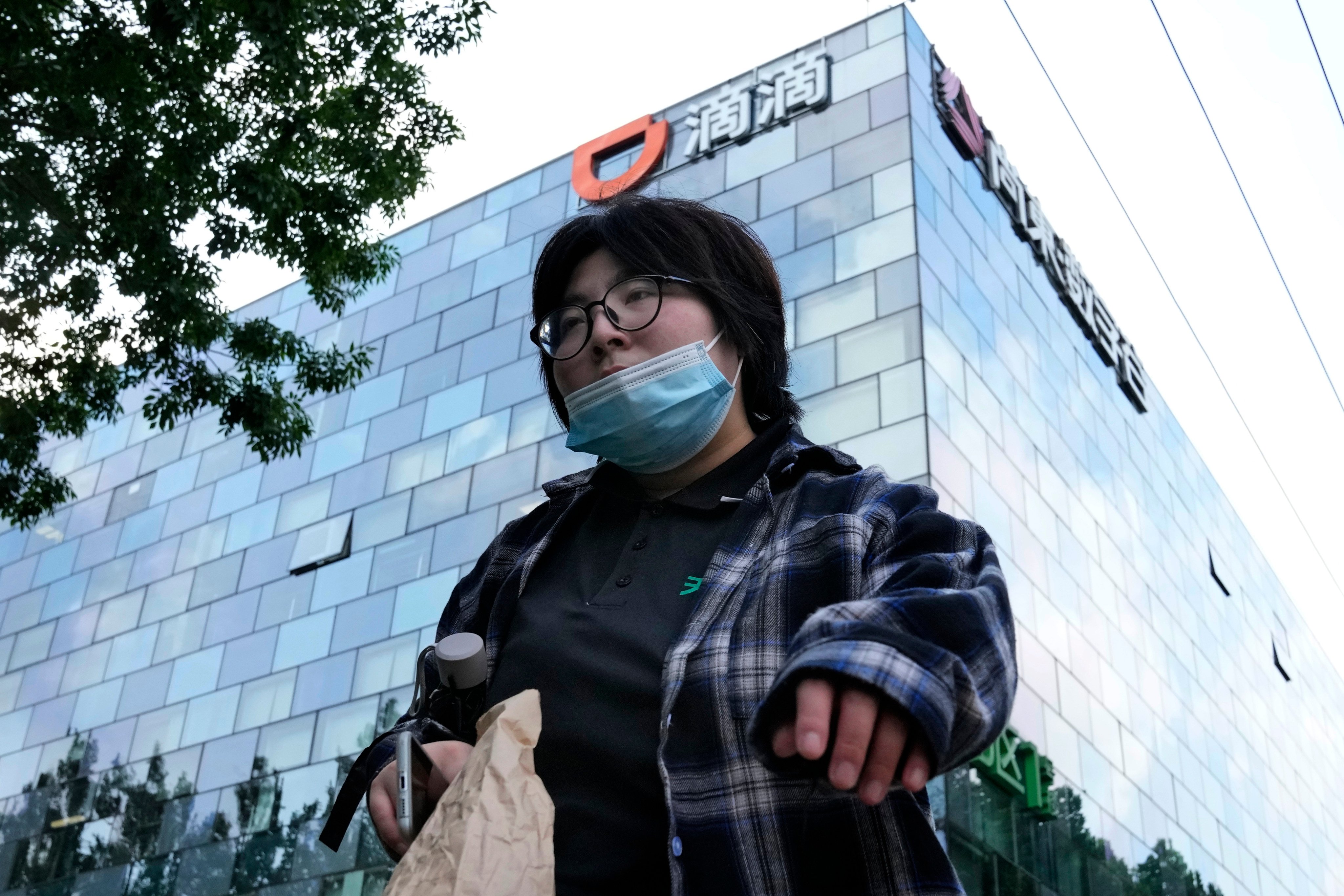 A pedestrian walks past the headquarters for Didi Global in Beijing. Photo: AP Photo