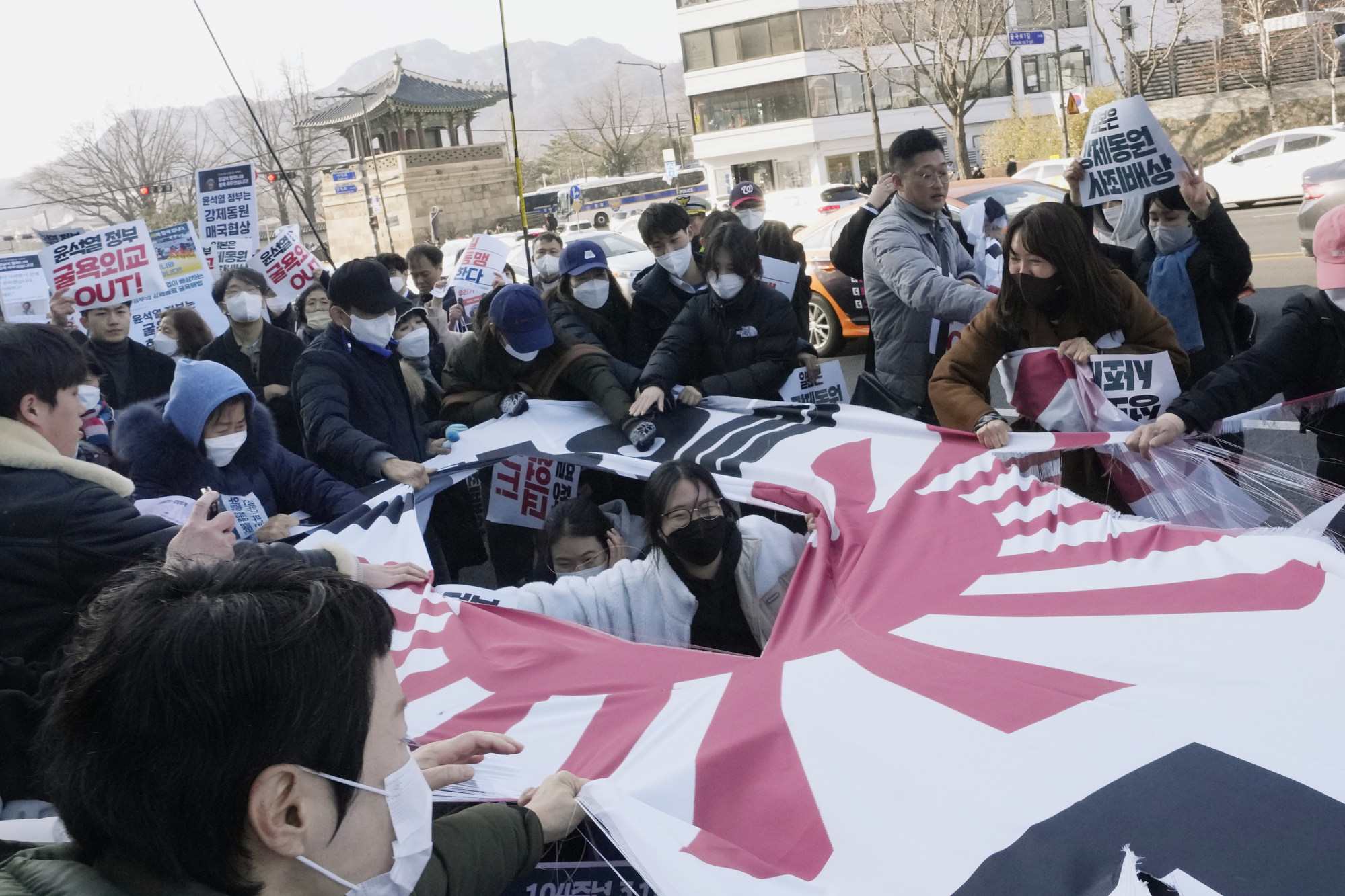 Protesters tear a banner with the Japanese rising-sun flag during a rally against the South Korean government’s move to improve relations with Japan, in front of the Japanese embassy in Seoul in March. Photo: AP