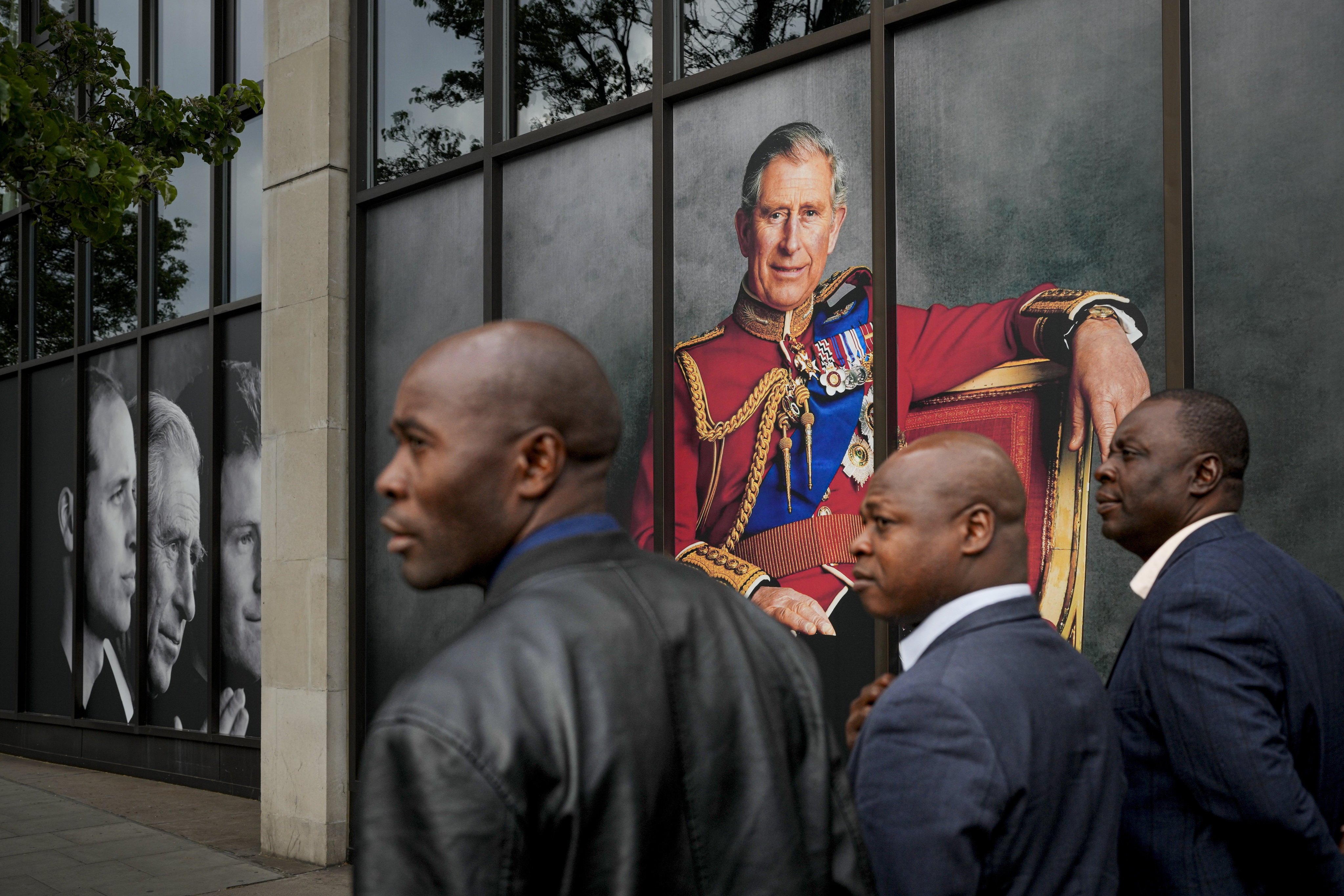 Men walk by a portrait of King Charles in London.  Jamaica and Belize are looking at ditching the British king as their head of state. Photo: AP