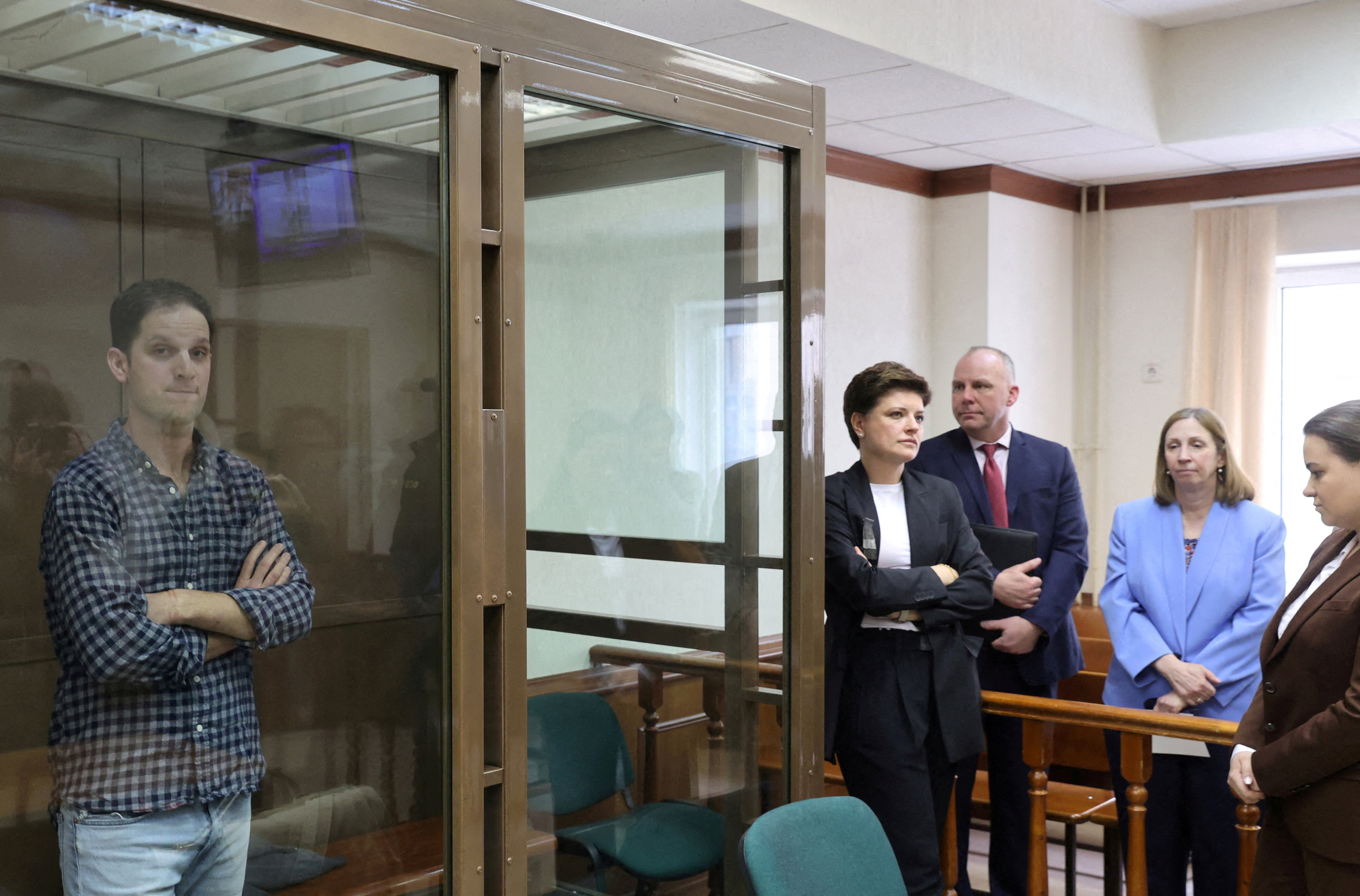 Wall Street Journal reporter Evan Gershkovich, who was detained in Russia while on a reporting trip and charged with espionage, stands behind a glass wall of an enclosure for defendants in a Moscow court. Photo: Reuters