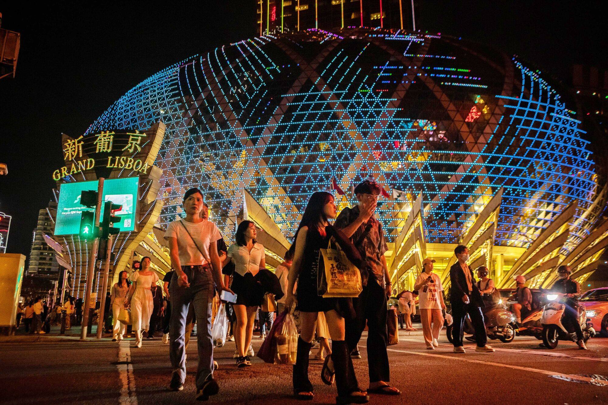 Visitors cross the street in front of the Grand Lisboa casino resort, operated by SJM Holdings Ltd., during Golden Week at night in Macau, China, on Sunday, April 30, 2023. Photo: Bloomberg