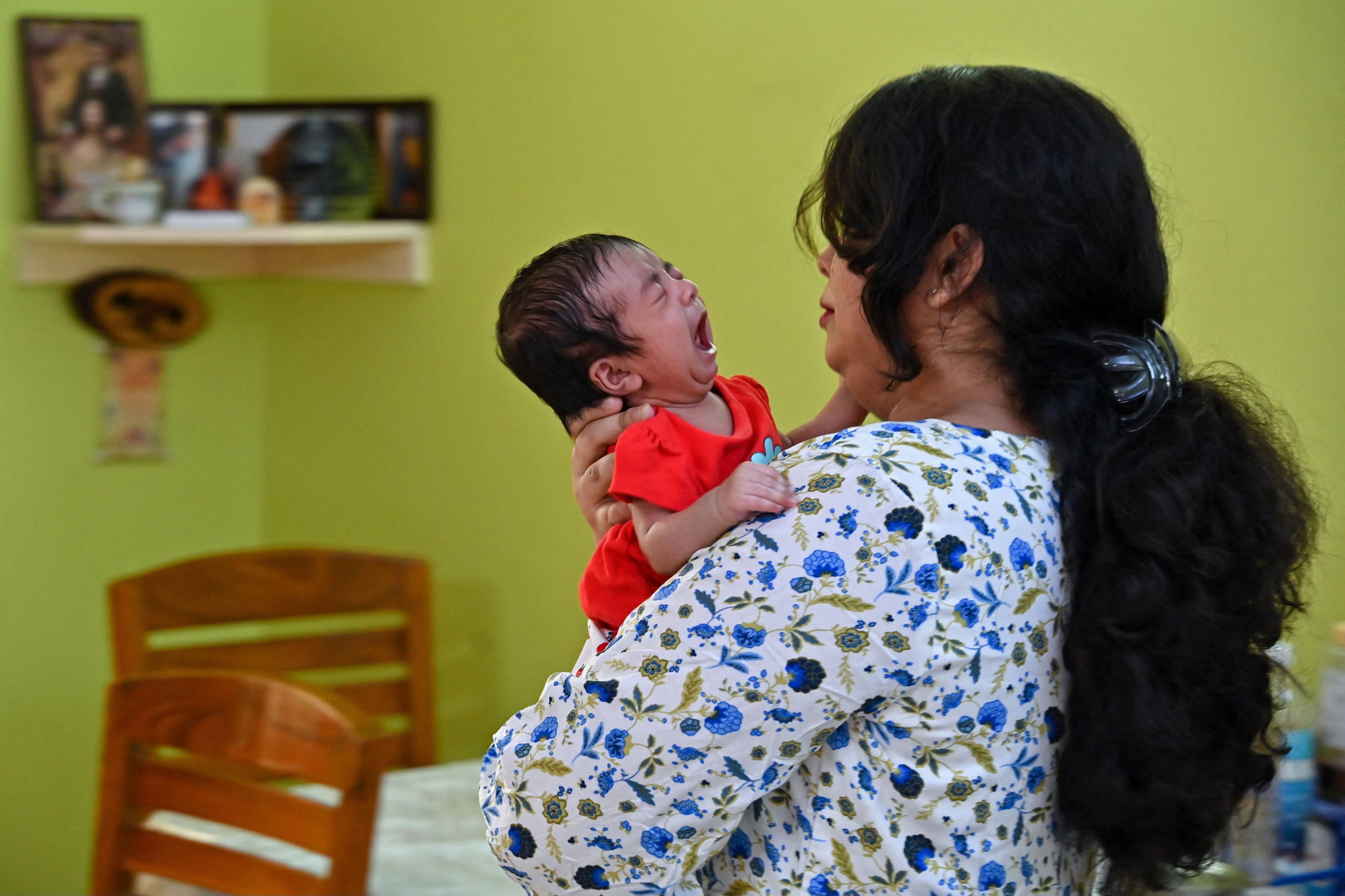 A mother soothes her baby at their home in Bengaluru. Photo: AFP 