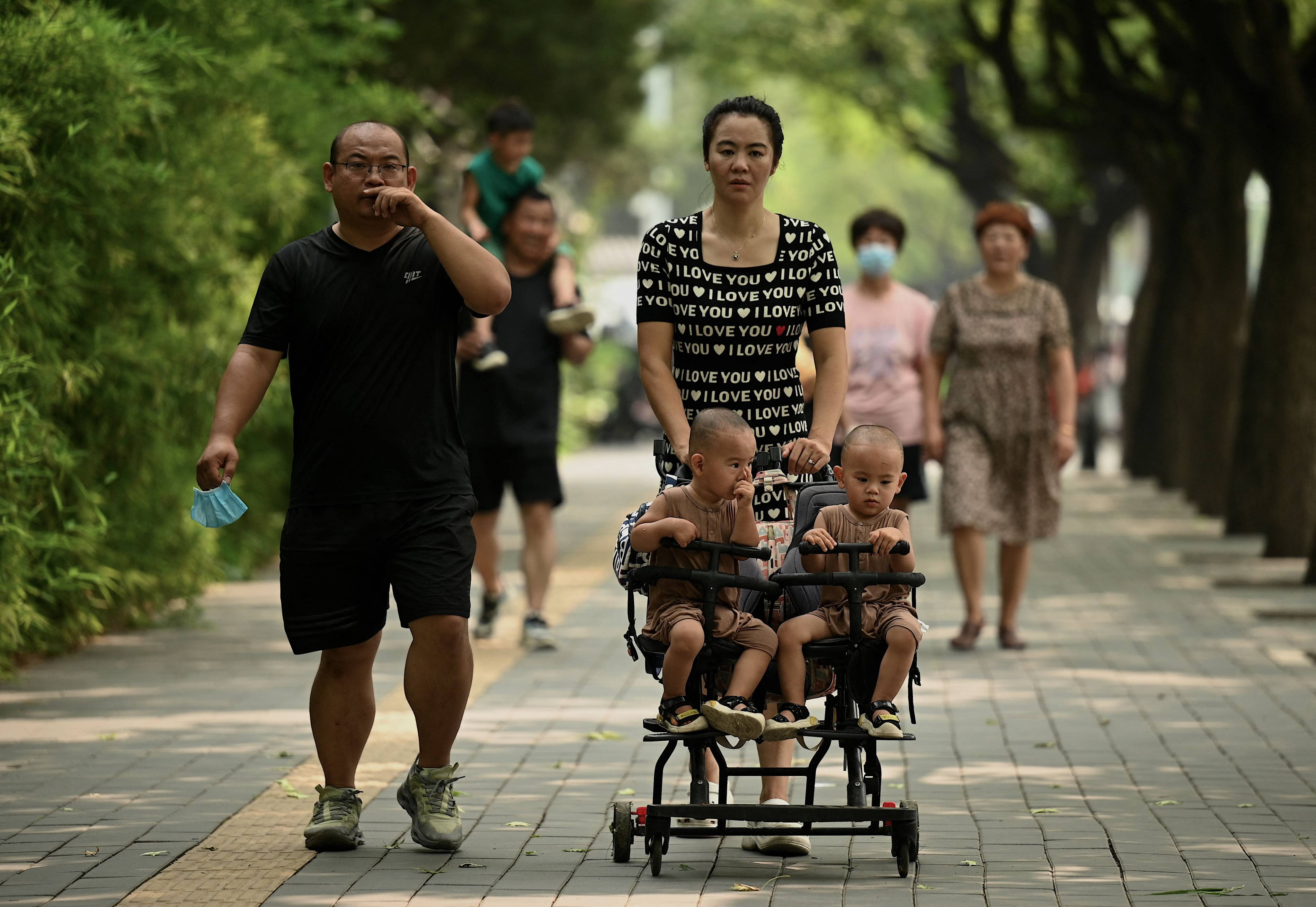 A woman pushes twins in a pram along a street in Beijing on August 16, 2022. China announced a slew of perks aimed at encouraging families to have more babies, as birth rates hit a record low. Photo: AFP