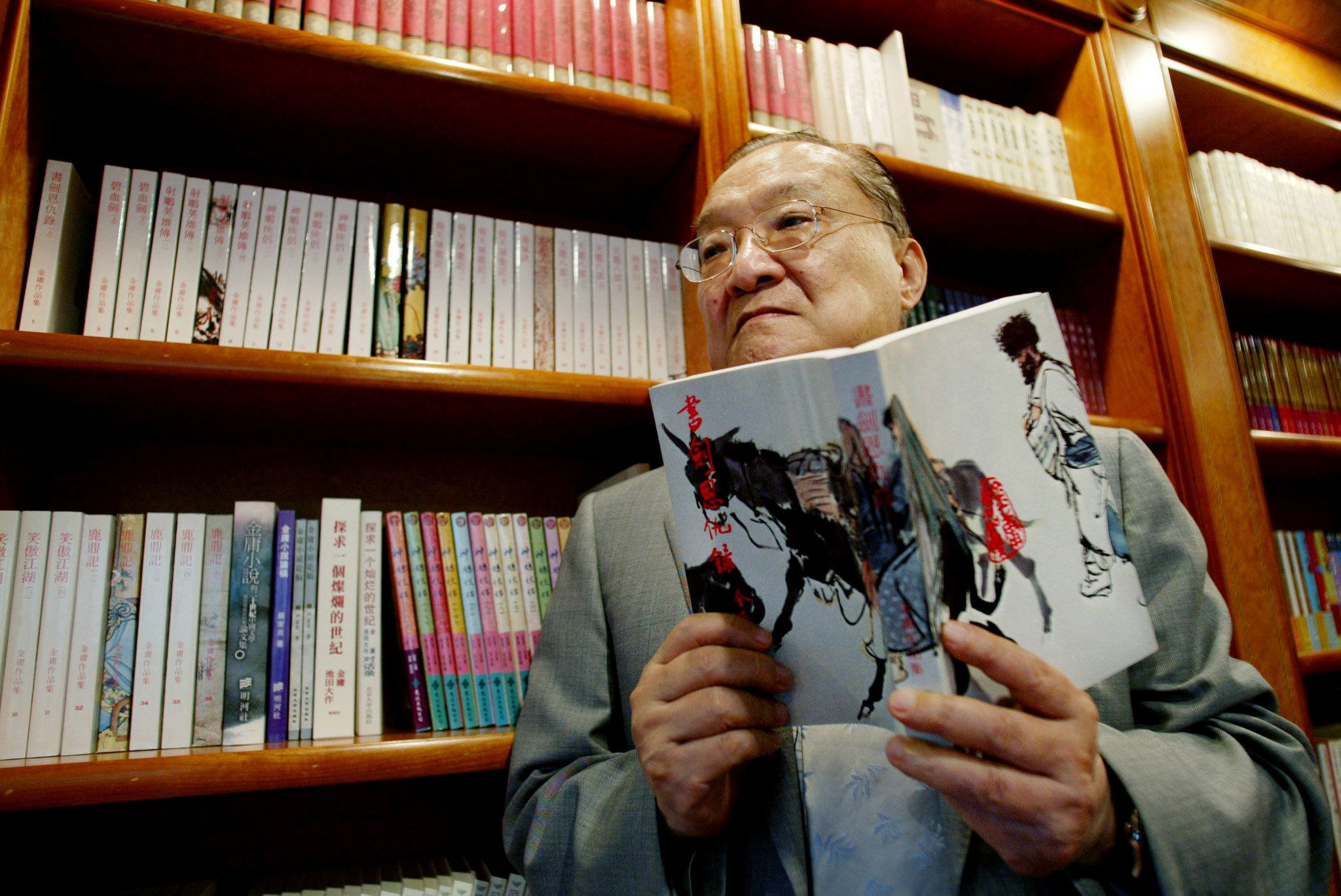 Hong Kong wuxia author Louis Cha Leung-yung, known by his pen name Jin Yong, holds a copy of his novel “Book and Sword, Gratitude and Revenge” at his office in the city on July 29, 2002. Photo: Reuters