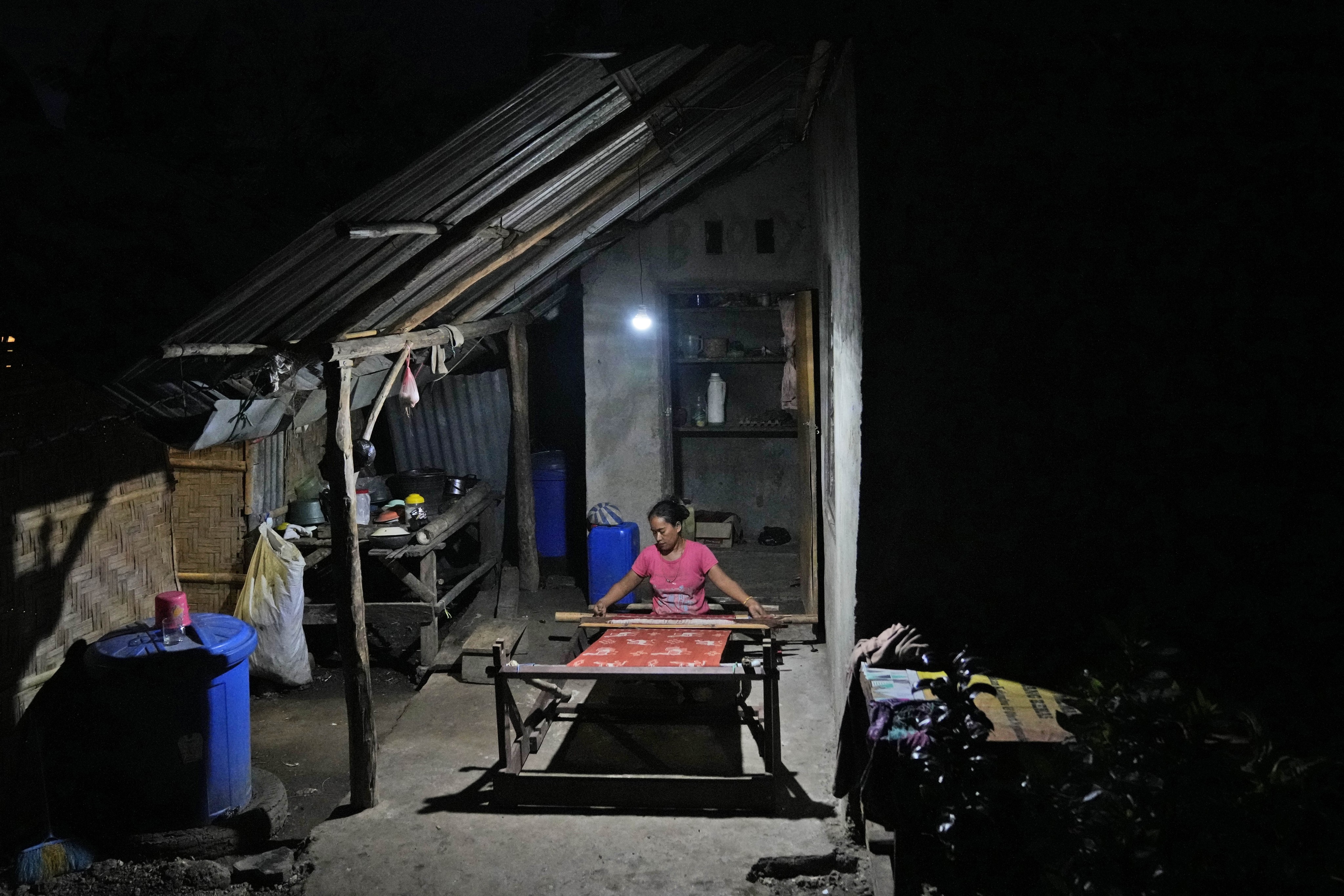 Tamar Ana Jawa is illuminated by a solar-powered light as she weaves a traditional cloth at a neighbour’s house in Laindeha village on Sumba Island, Indonesia, on March 22, 2023. Photo: AP