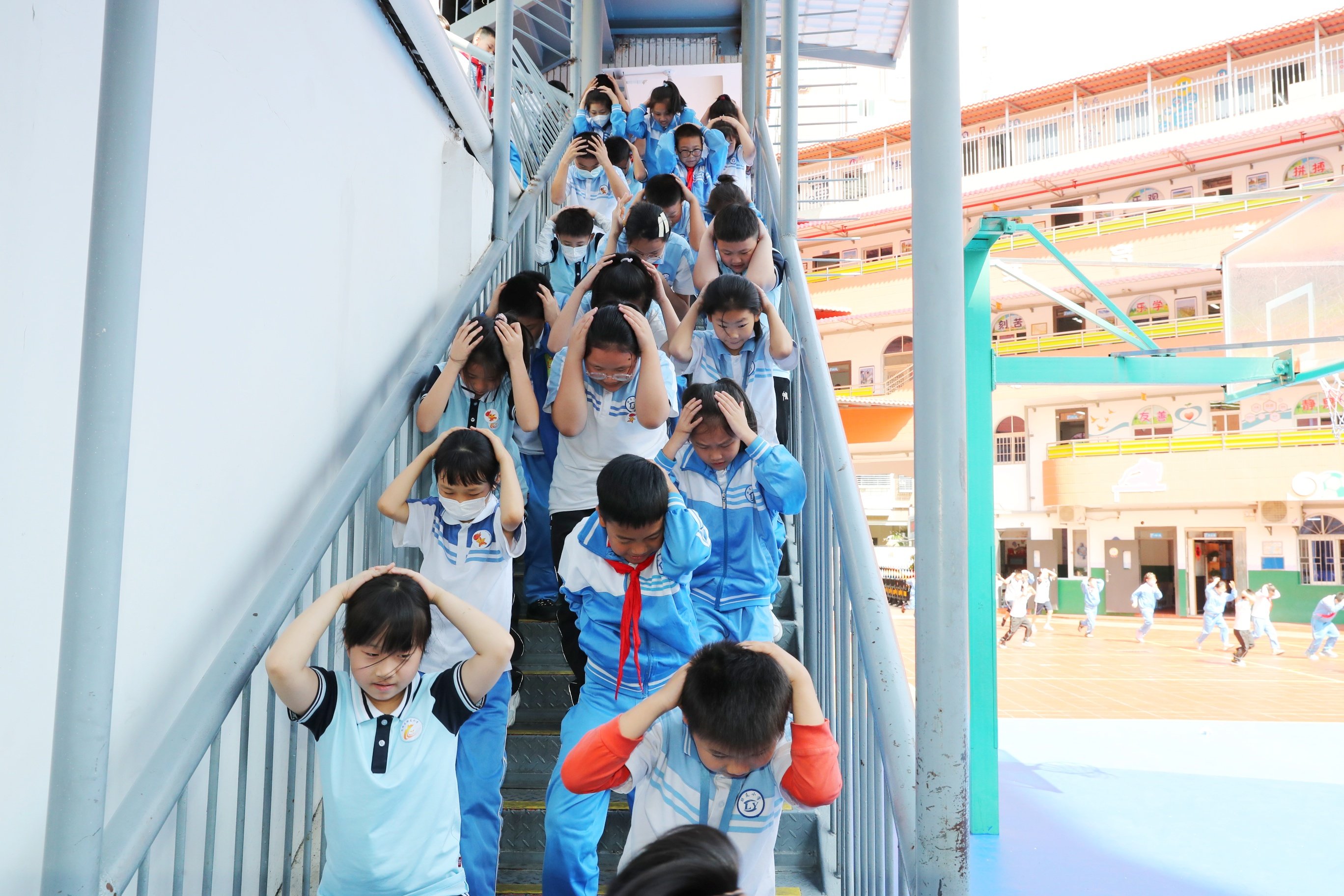 Primary school students cover their heads and rush downstairs from their classrooms during the annual air defence exercises in Xiamen, Fujian province, on May 10. Photo: Imaginechina
