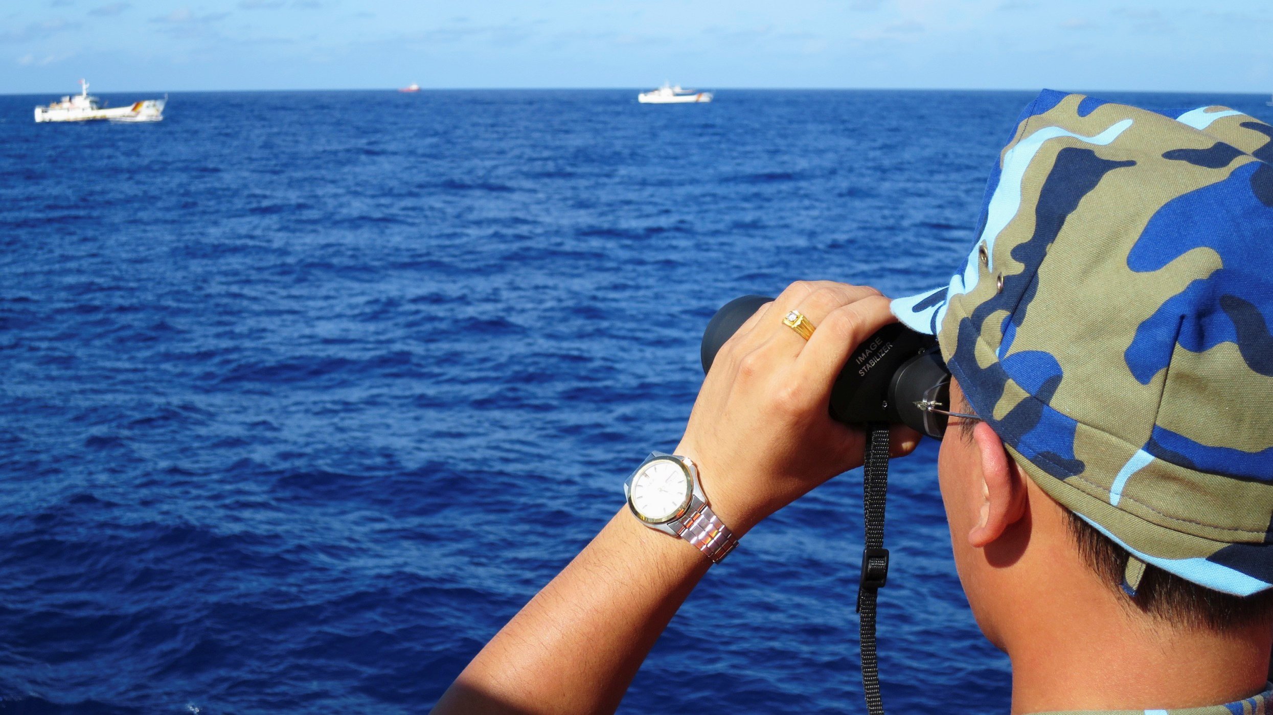 A crewman from a Vietnamese coastguard ship ooks out at Chinese coastguard vessels. Photo: Reuters