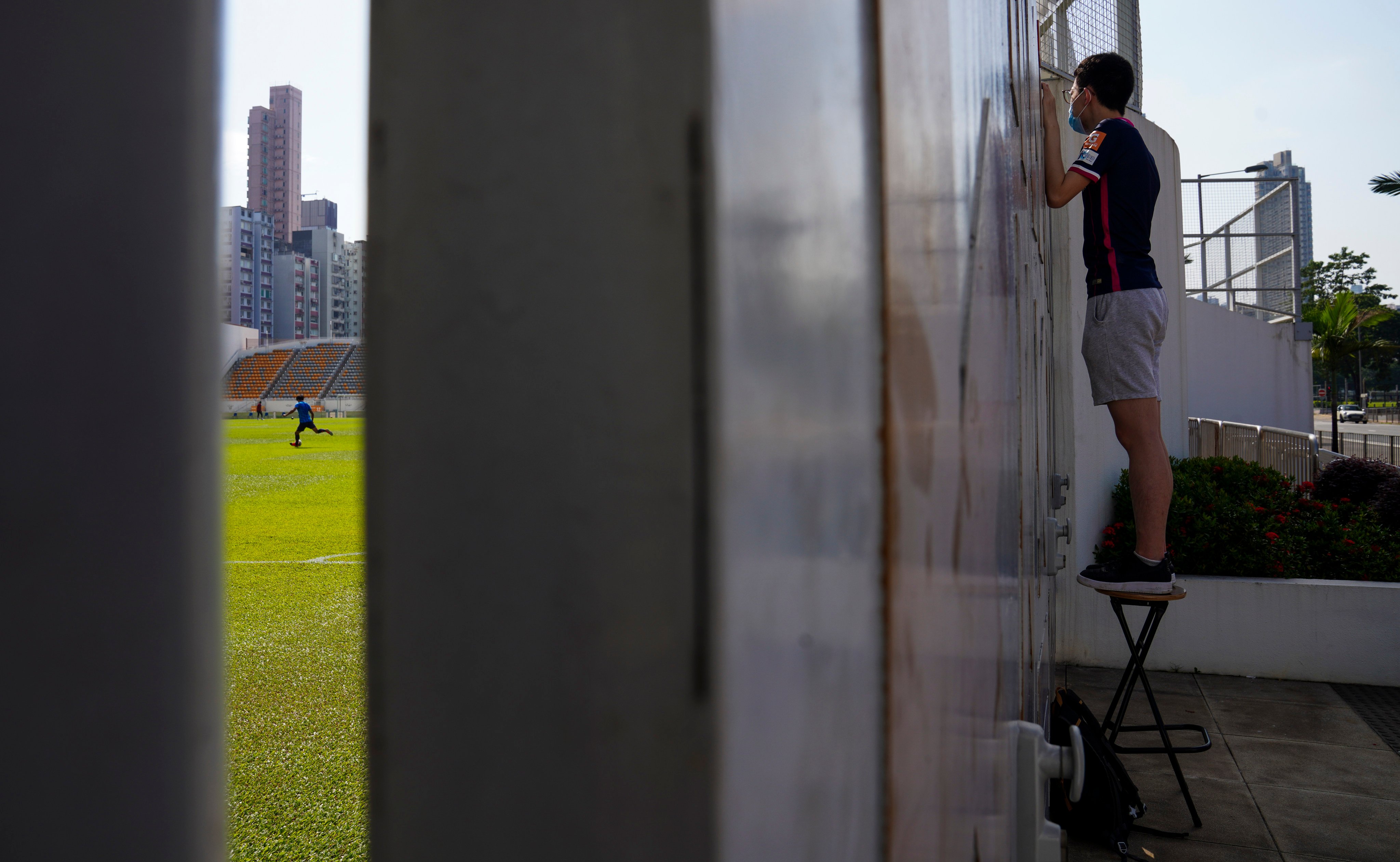 A football fan tries to get a glimpse of a closed-door match at Mong Kok Stadium in October 2020, during the pandemic. Though no longer in its heyday, Hong Kong football still draws some diehard fans. Photo: Sam Tsang