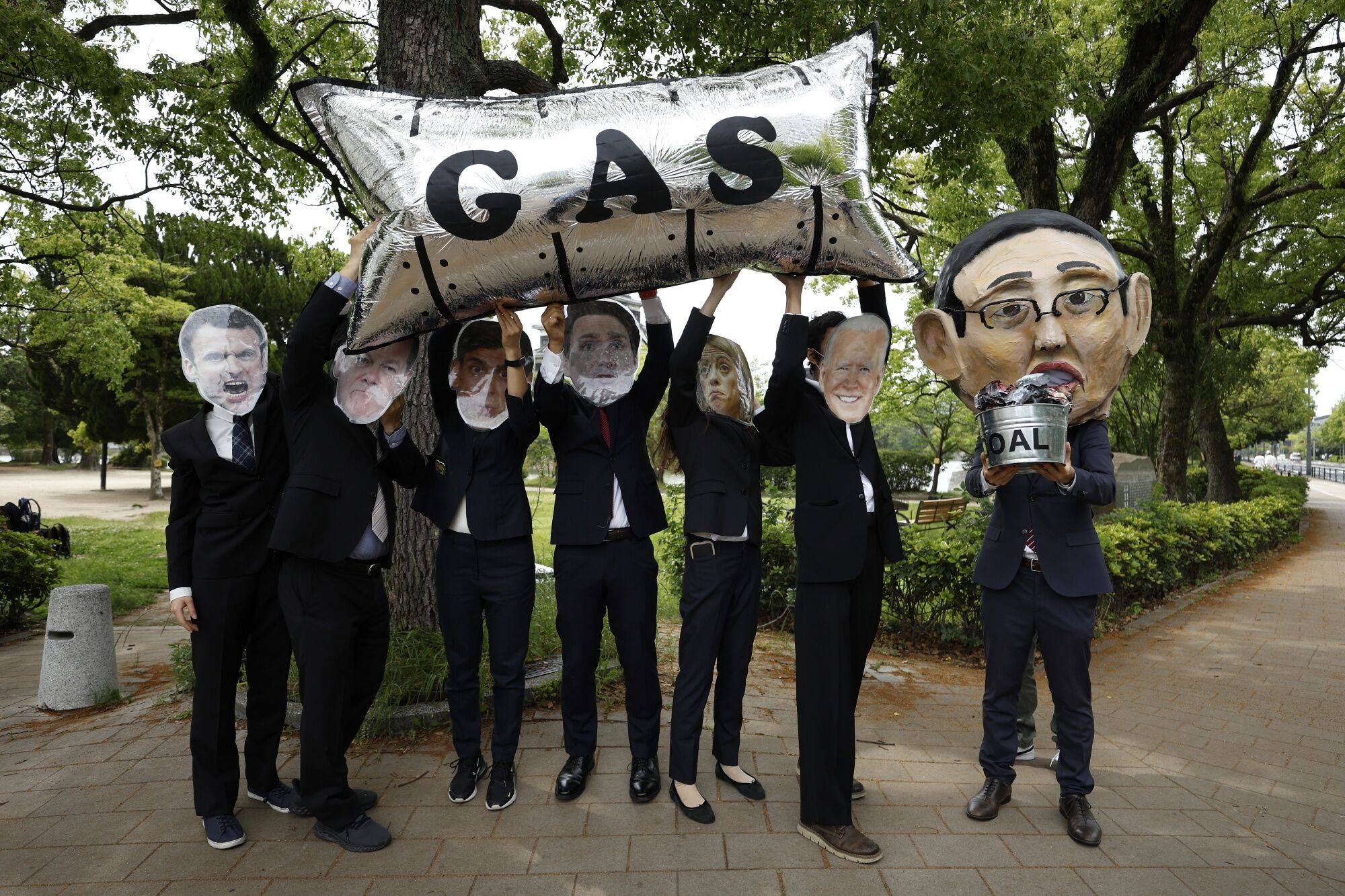 An activist wearing a mask depicting Japanese Prime Minister Fumio Kishida (right) holds a basket of mock-up coal while others depict other G7 leaders during a protest in Japan against fossil fuels. Photo: Bloomberg