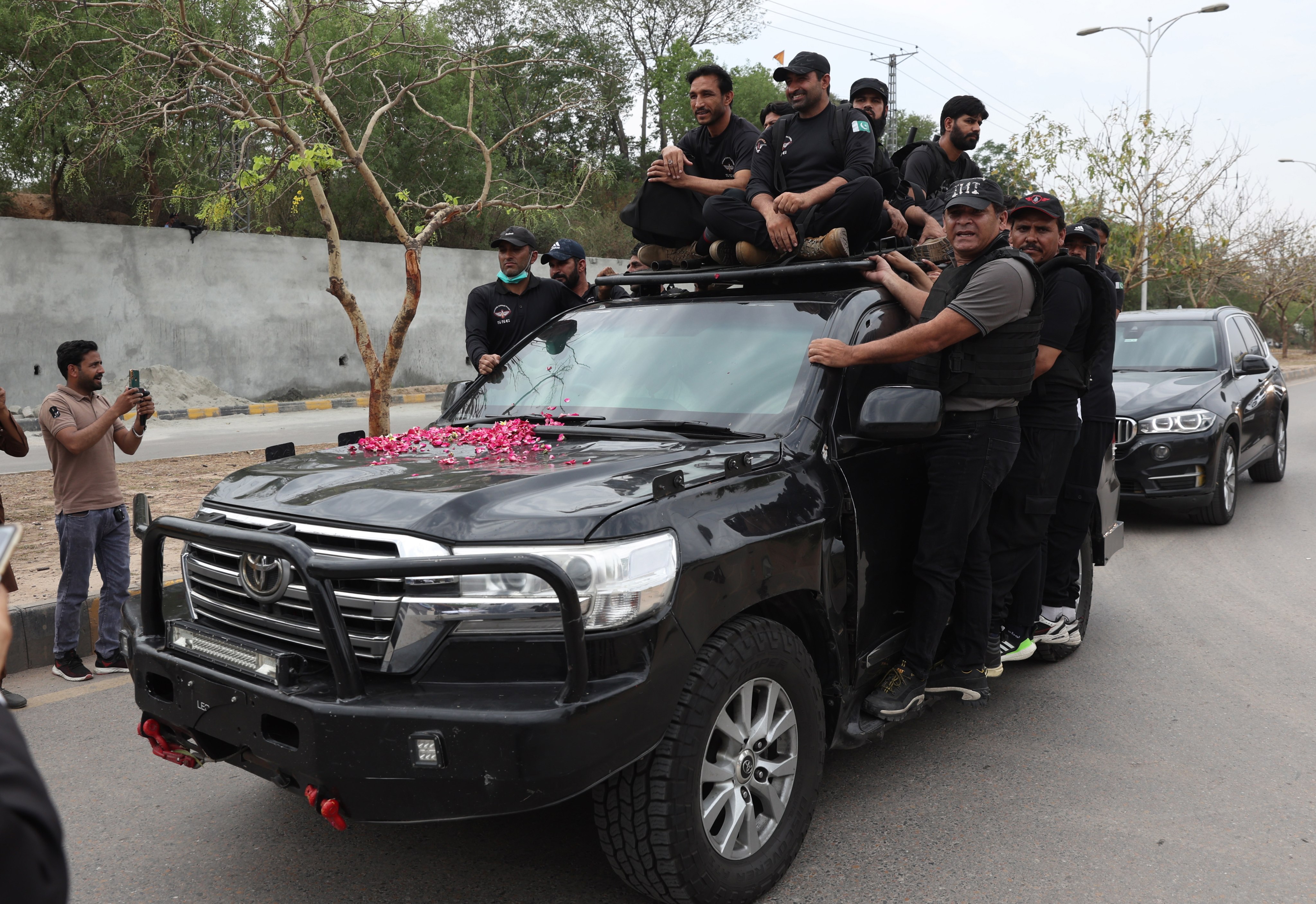 Private security personnel escort a vehicle transporting former Prime Minister Imran Khan to court to get bail on Tuesday in cases related to the violence that erupted in March between his supporters and police. Photo: EPA-EFE