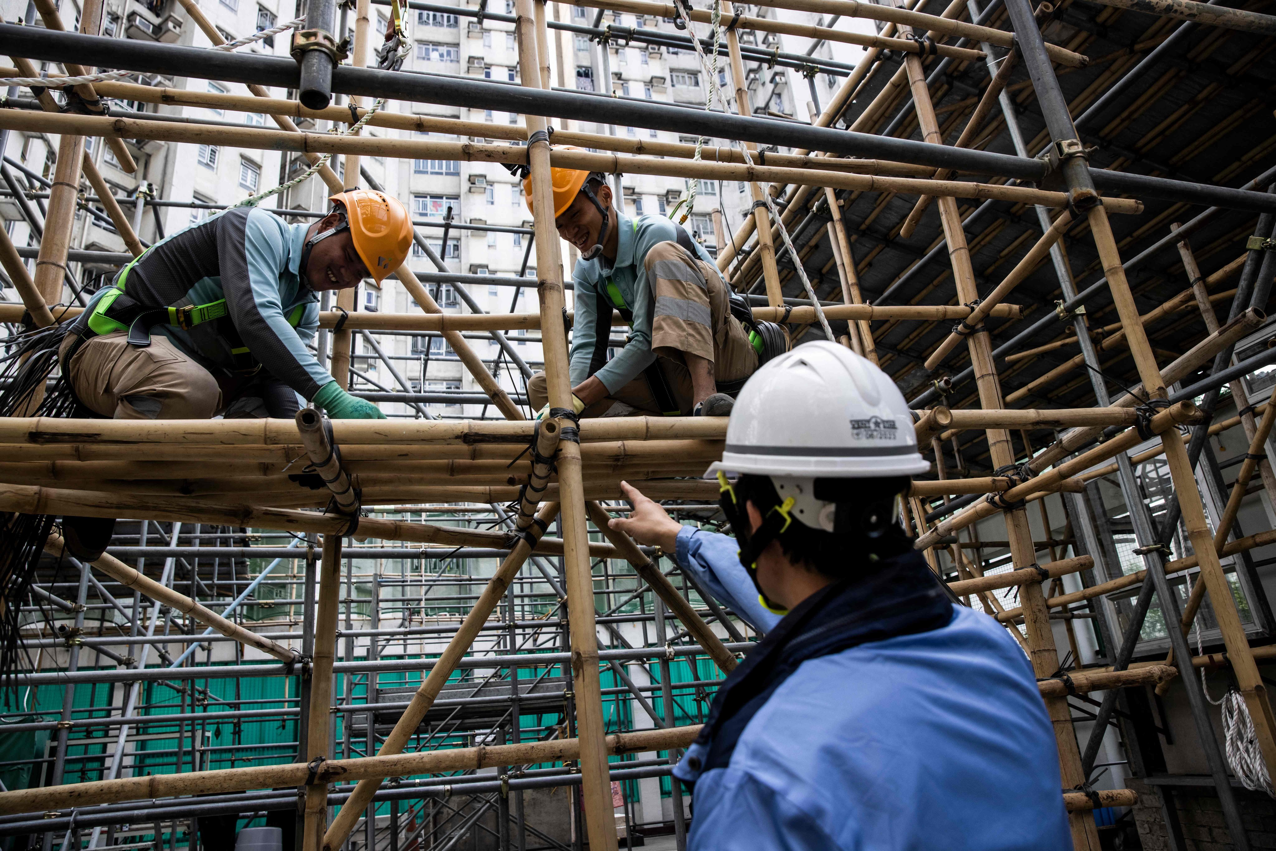 Ho Cheuk-wai (left) and Mo Jia-Yu (top right) receive instructions during a bamboo scaffolding class. Photo: AFP