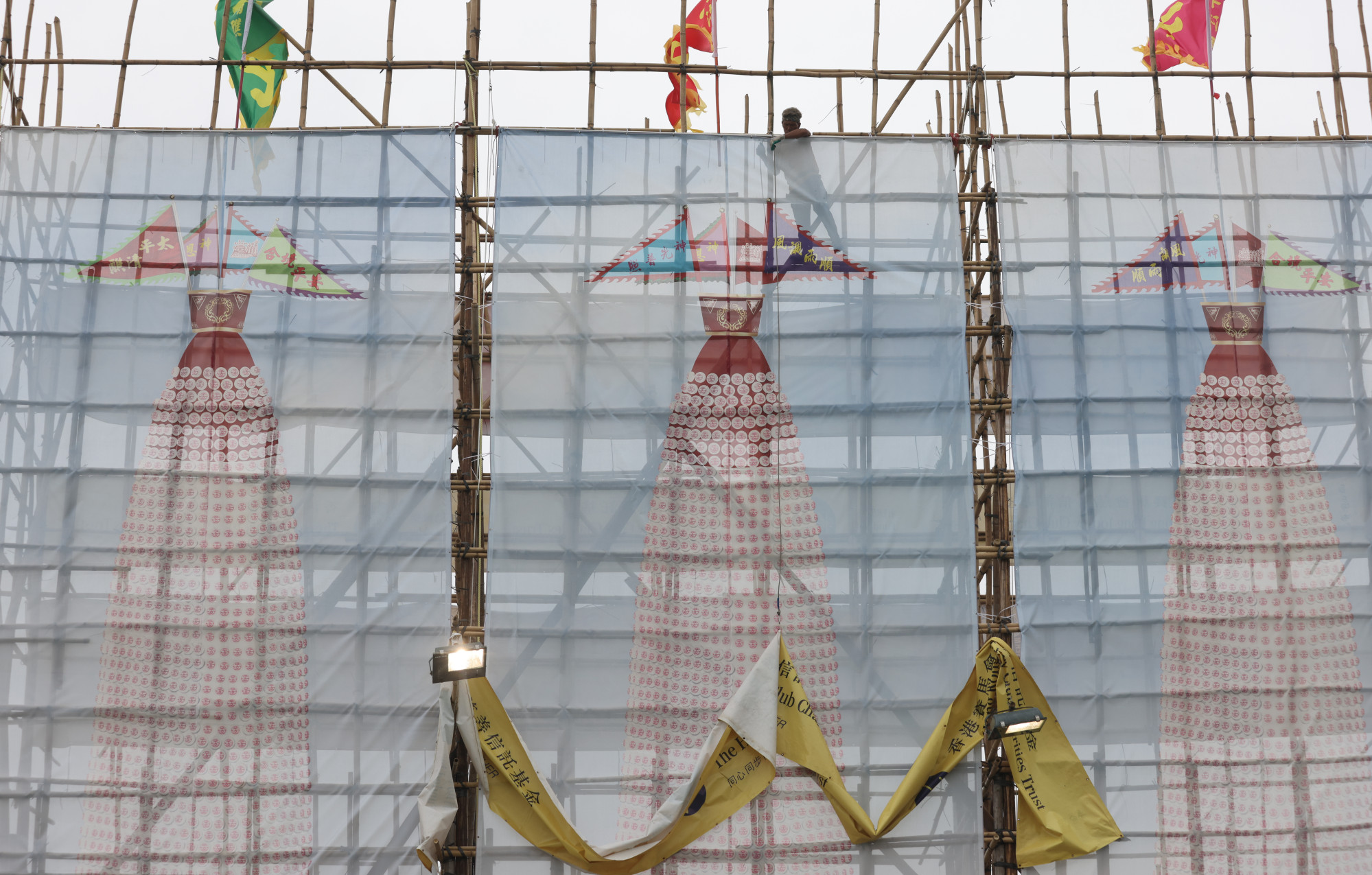 Workers erecting banners to show the normal height of decorative towers that have been downsized for this year’s event. Photo: May Tse