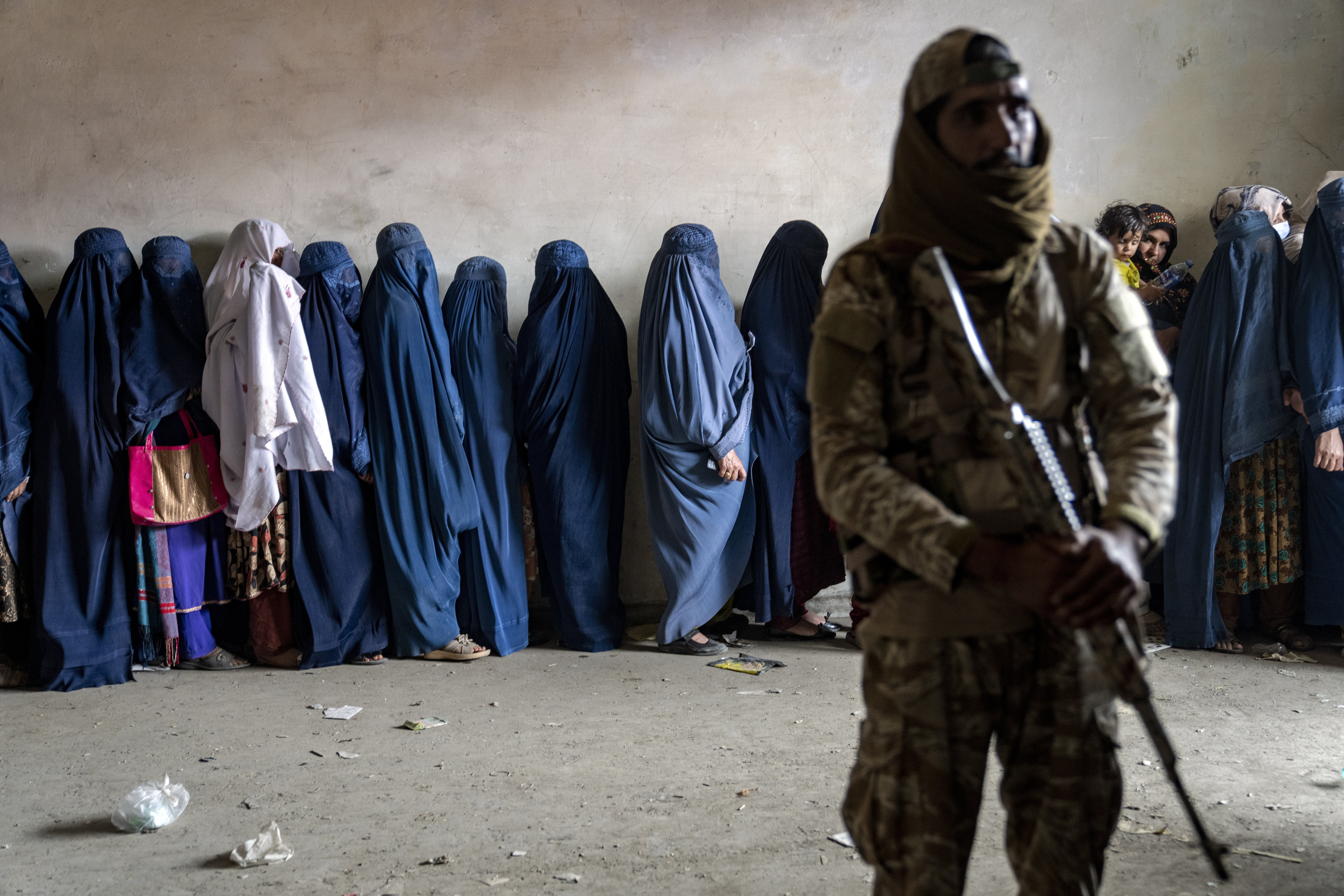 A Taliban fighter stands guard as women wait to receive food rations distributed by a humanitarian aid group in Kabul, Afghanistan, on May 23. Photo: AP