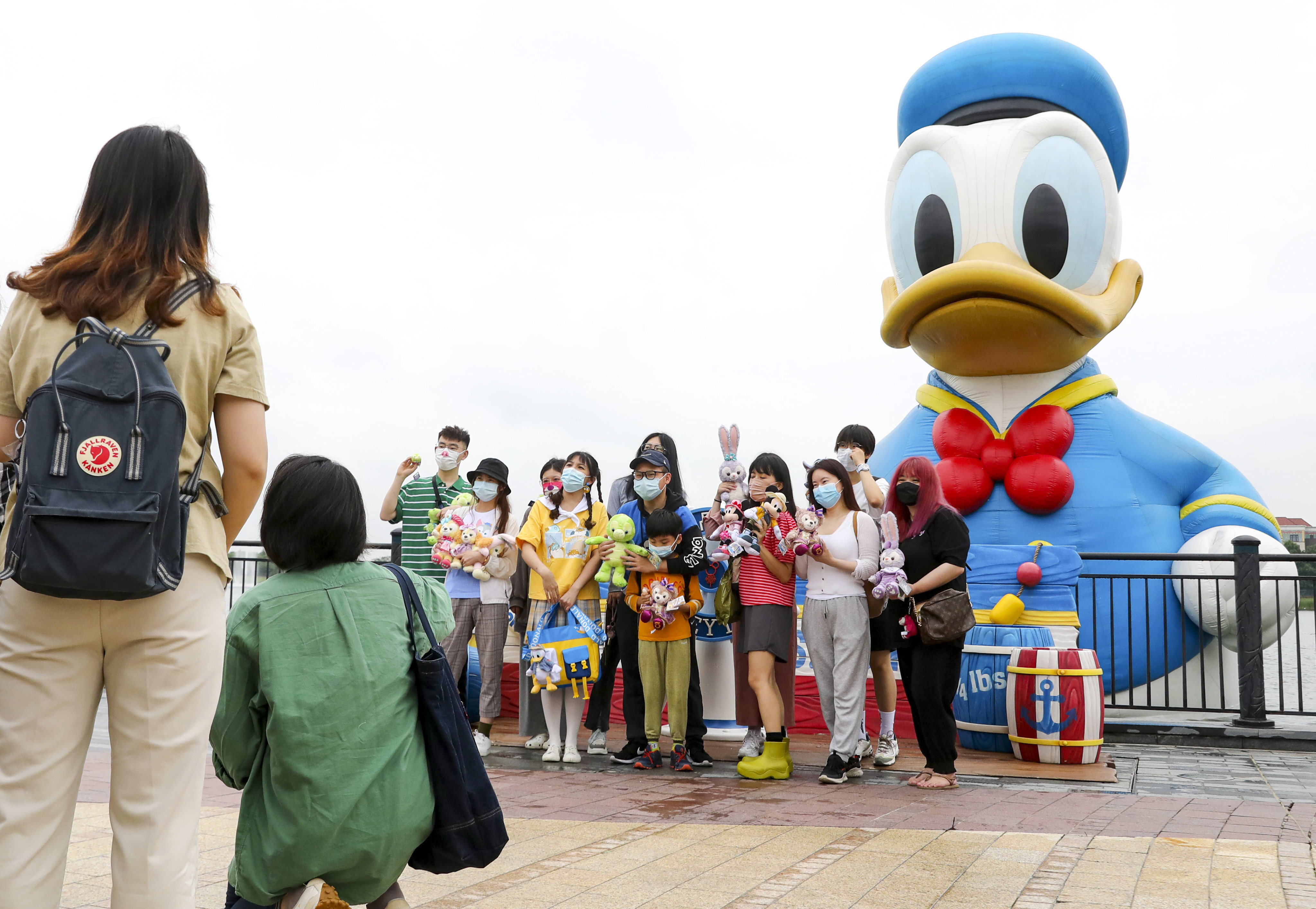 Tourists pose with an inflatable doll of Donald Duck at Wishing Star Park of Disney Resort in Shanghai. The theme park is raising ticket prices from next month. Photo: Xinhua