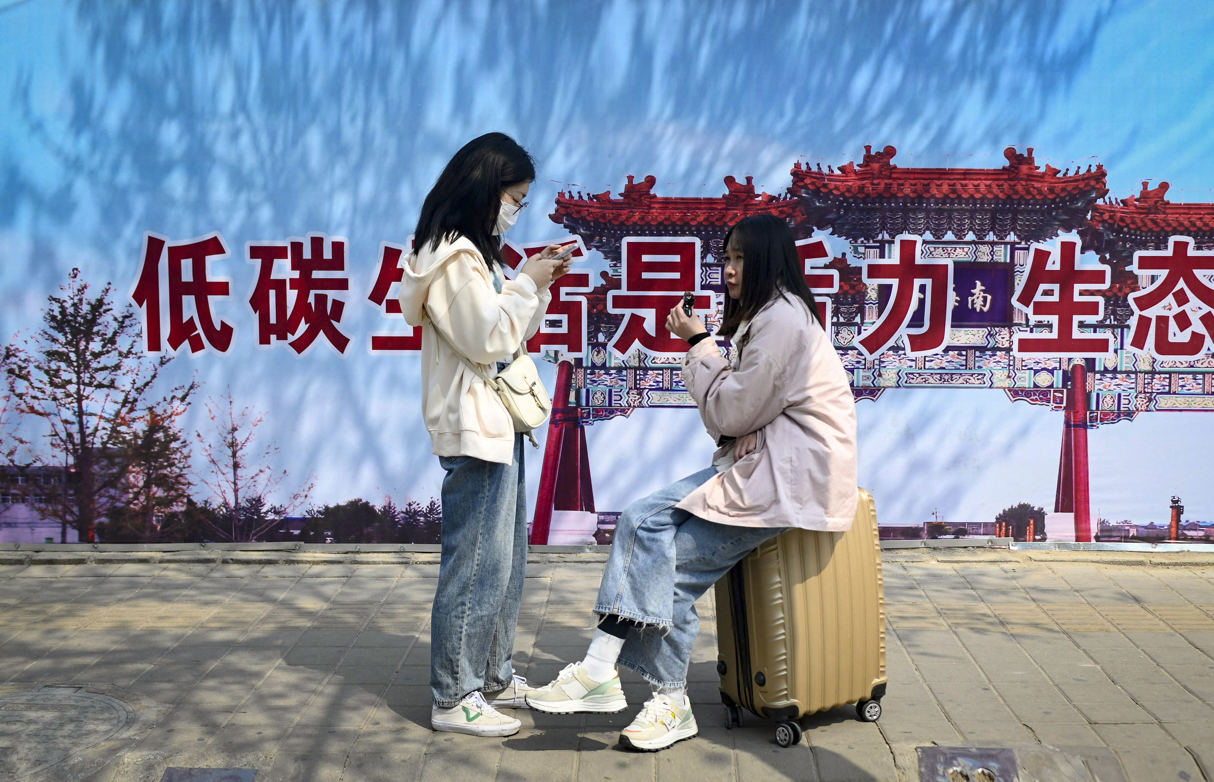People wait at a bus stop in Beijing with a slogan promoting low-carbon living in Beijing. Photo: AFP