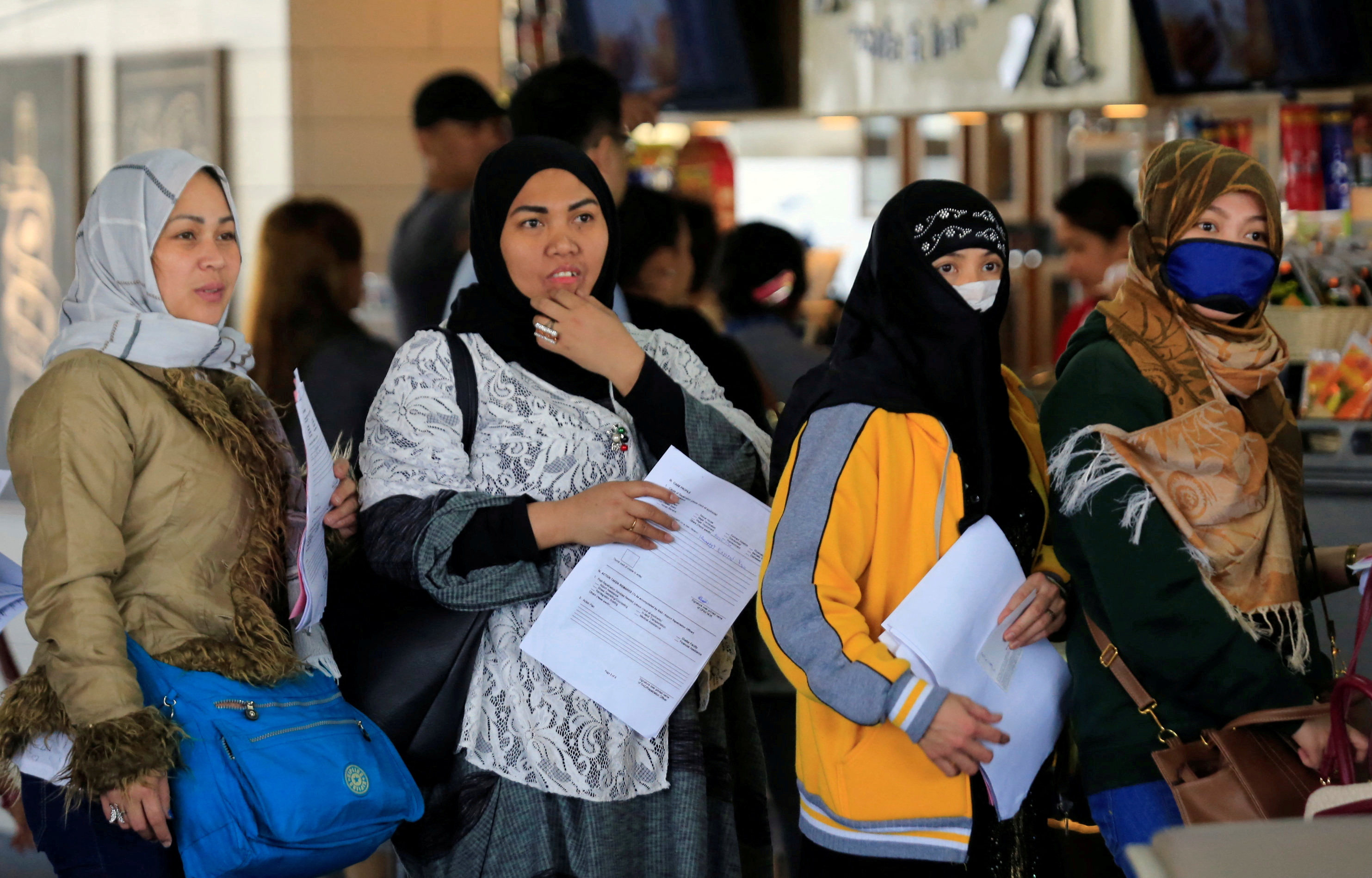 Overseas Filipino Workers from Kuwait hold their documents as they queue at the airport in Manila. Photo: Reuters