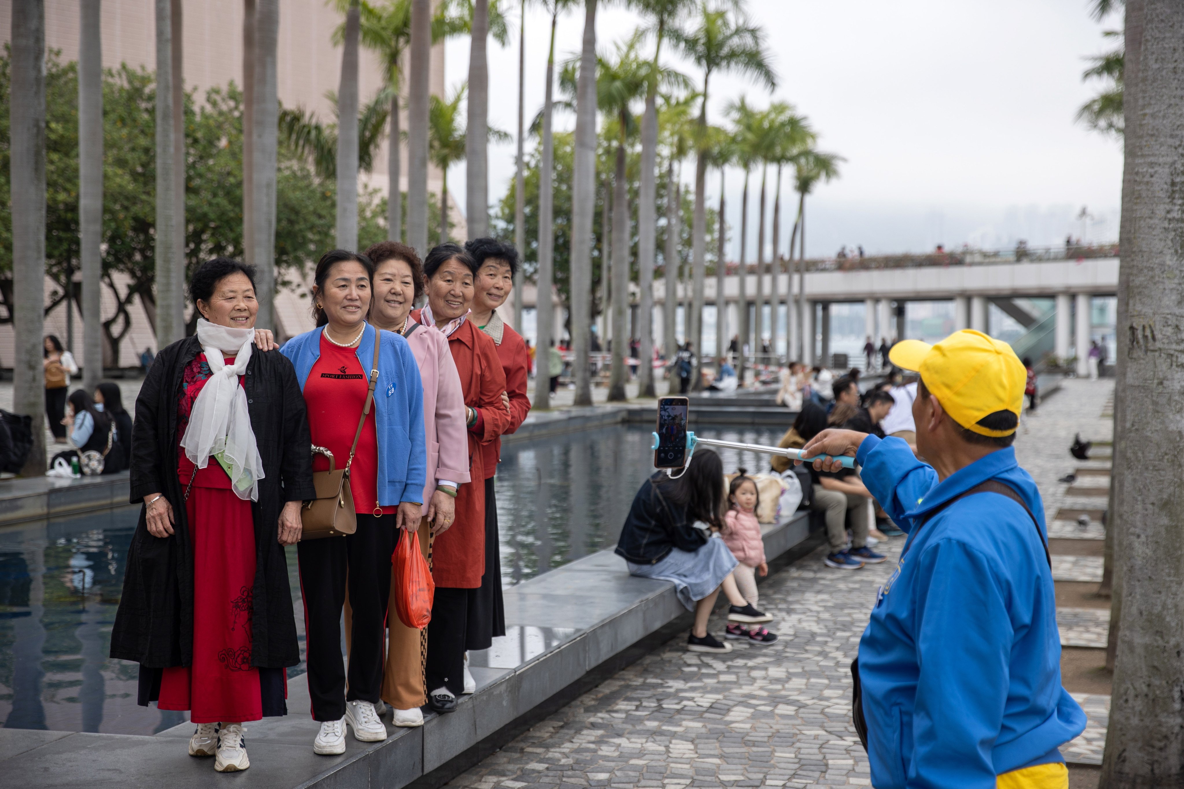 Mainland Chinese tourists, part of a tour group, pose for photos on the Tsim Sha Tsui waterfront in Hong Kong on March 30. Photo: EPA-EFE