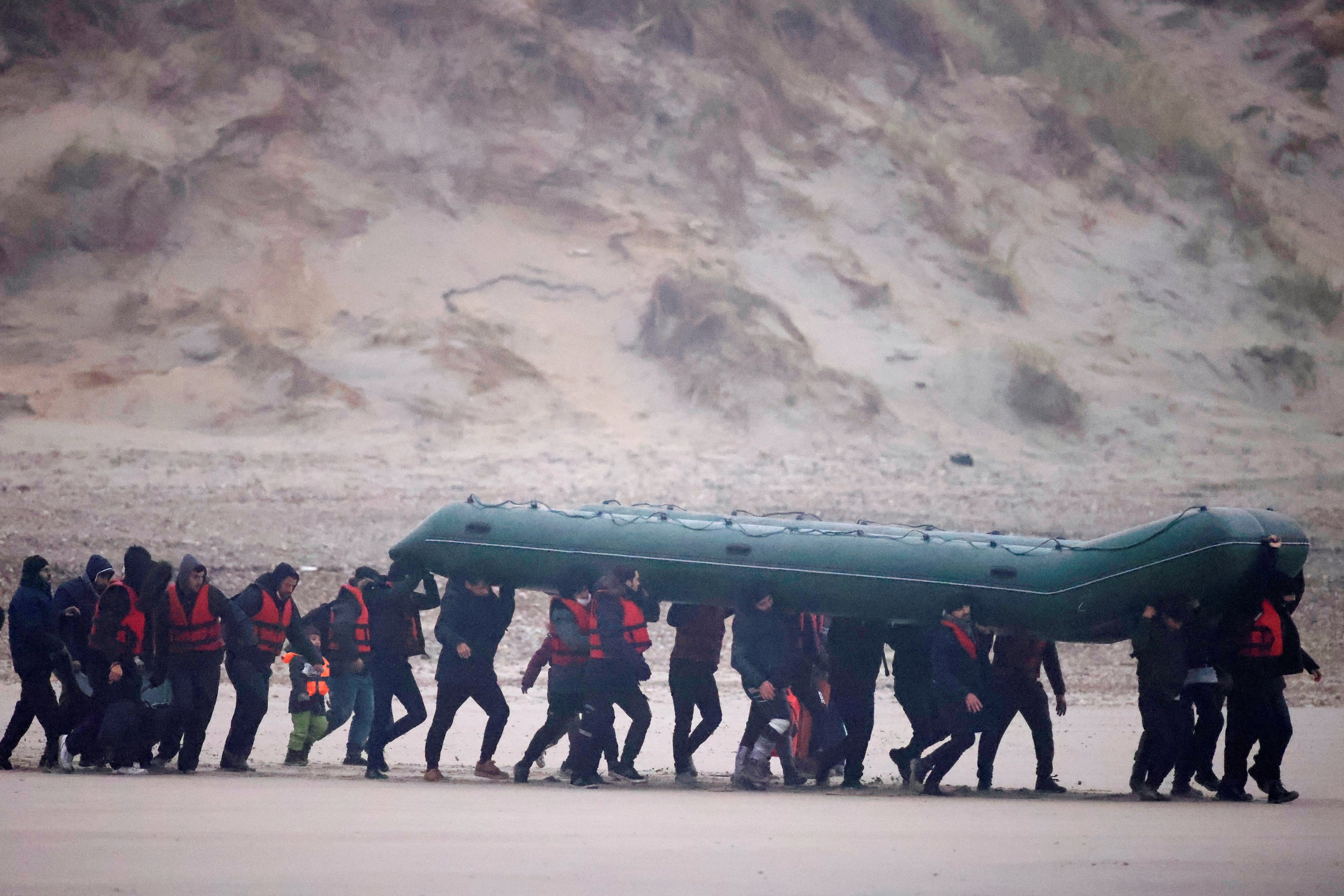 Migrants on a beach in France with an inflatable dinghy, preparing to cross the English Channel in November 2021. File photo: Reuters