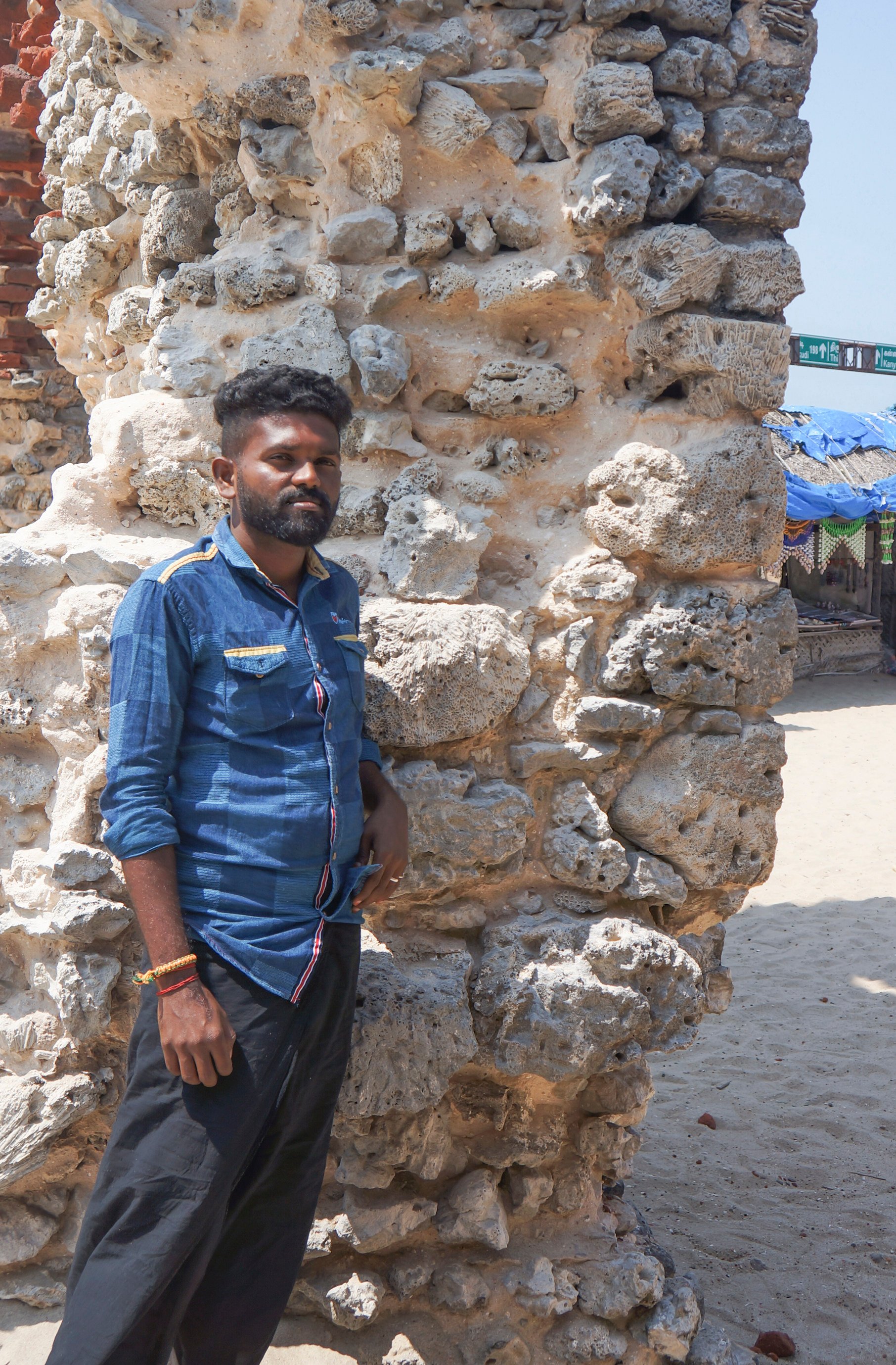 Vijidharan stands next to a pillar built of stone and coral in Danushkodi. Photo: Kamala Thiagarajan