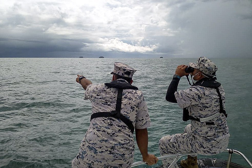 Malaysian Maritime Enforcement Agency personnel use binoculars to scan the sea. Photo: Malaysian Maritime Enforcement Agency handout via EPA-EFE