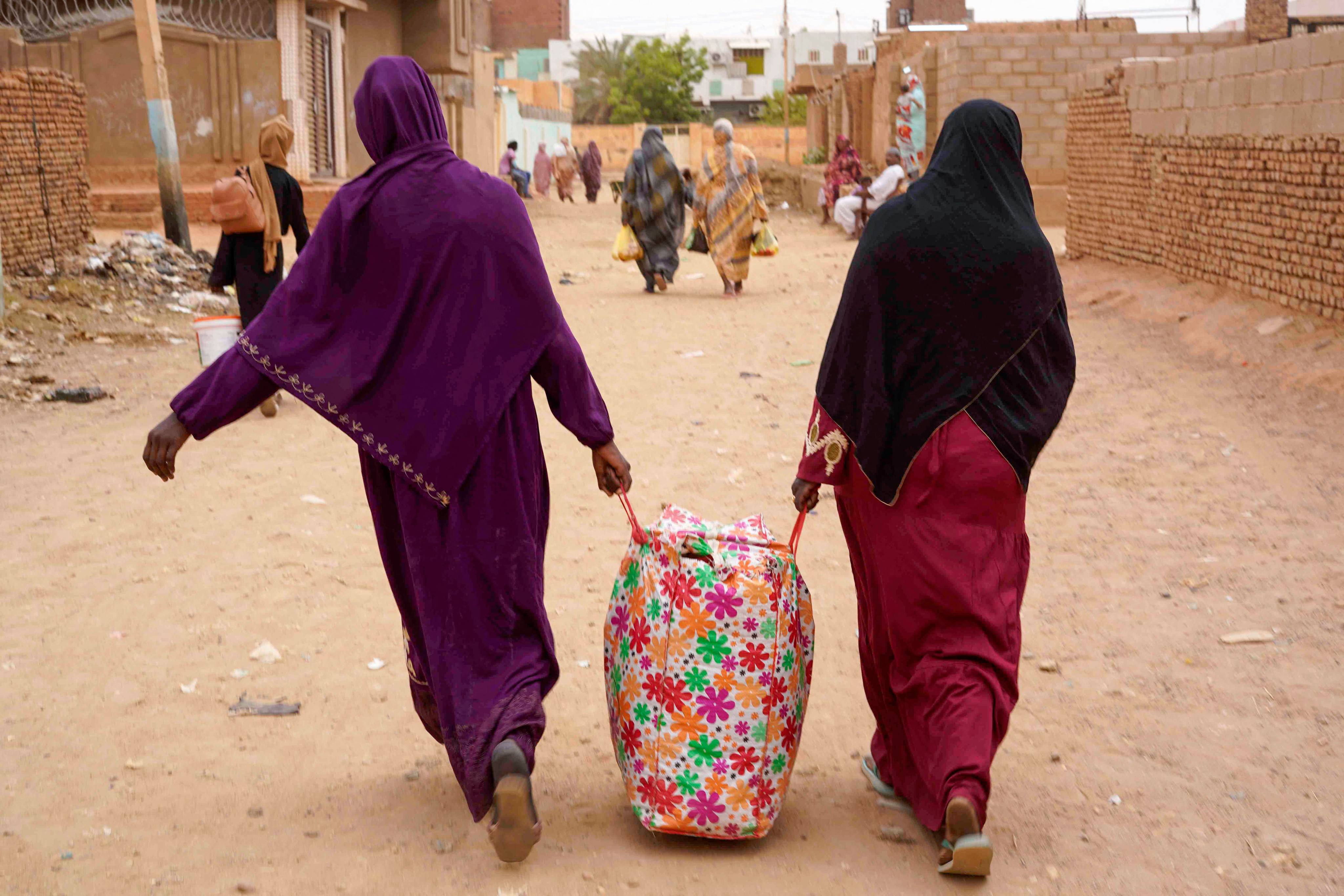 Women carrying belongings walk down a street in Omdurman, a city in war-torn Sudan, on Monday, the day a one-week ceasefire aiming to allow humanitarian aid for civilians is due to expire. Photo: AFP