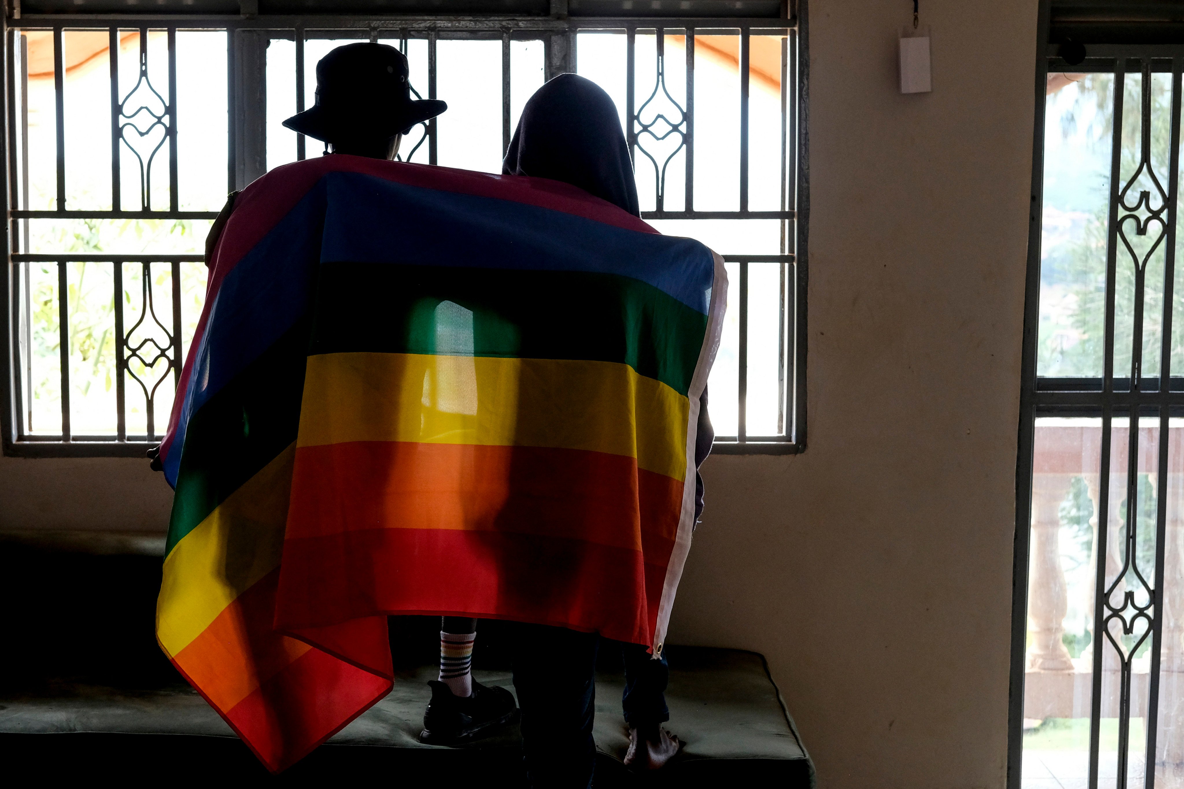 A gay Ugandan couple cover themselves with a pride flag as they pose for a photograph in Uganda in March. Photo: AP