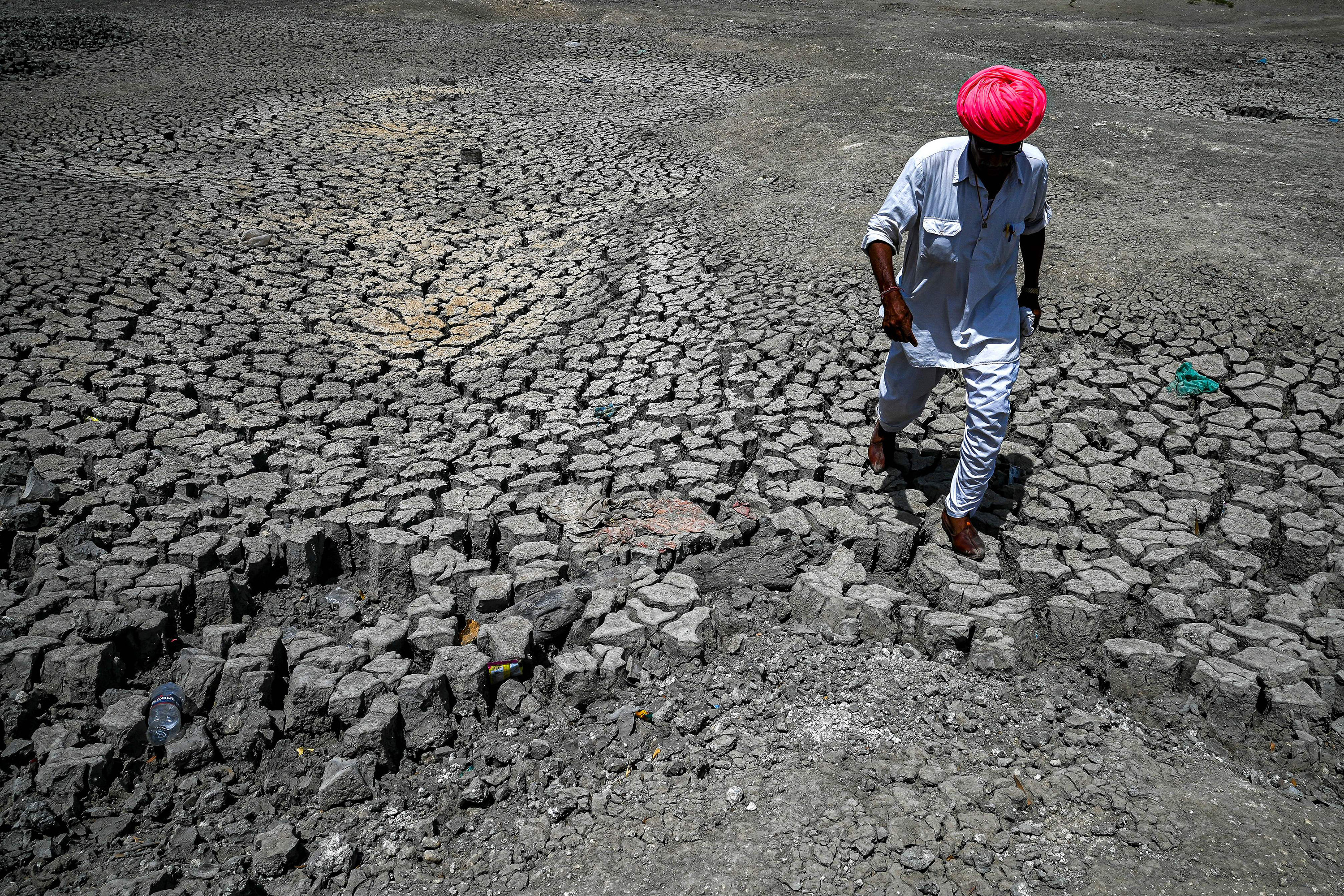 A villager walks through the cracked bottom of a dried-out pond on a hot summer day in India’s desert state of Rajasthan. Photo: AFP via Getty Images
