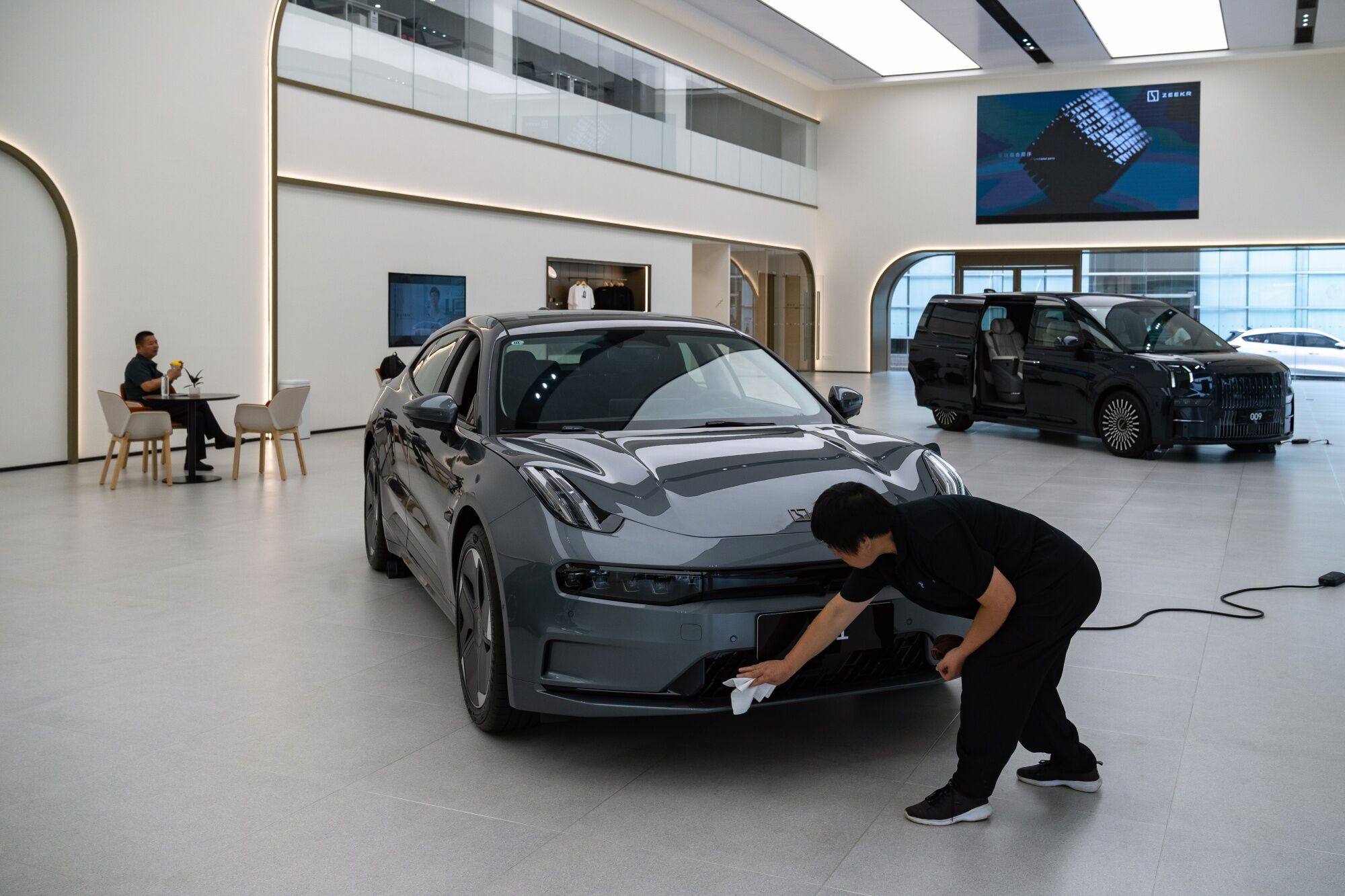 A woman clear a Zeekr EV in the showroom of a shop in Haikou, Hainan Province, China, on Tuesday, May 10, 2023. Hainan is the first and only place in China to set a goal to end the sale of fossil fuel cars by 2030 and have EVs and hybrids account for 45% of the island’s fleet. Photographer: Bloomberg
