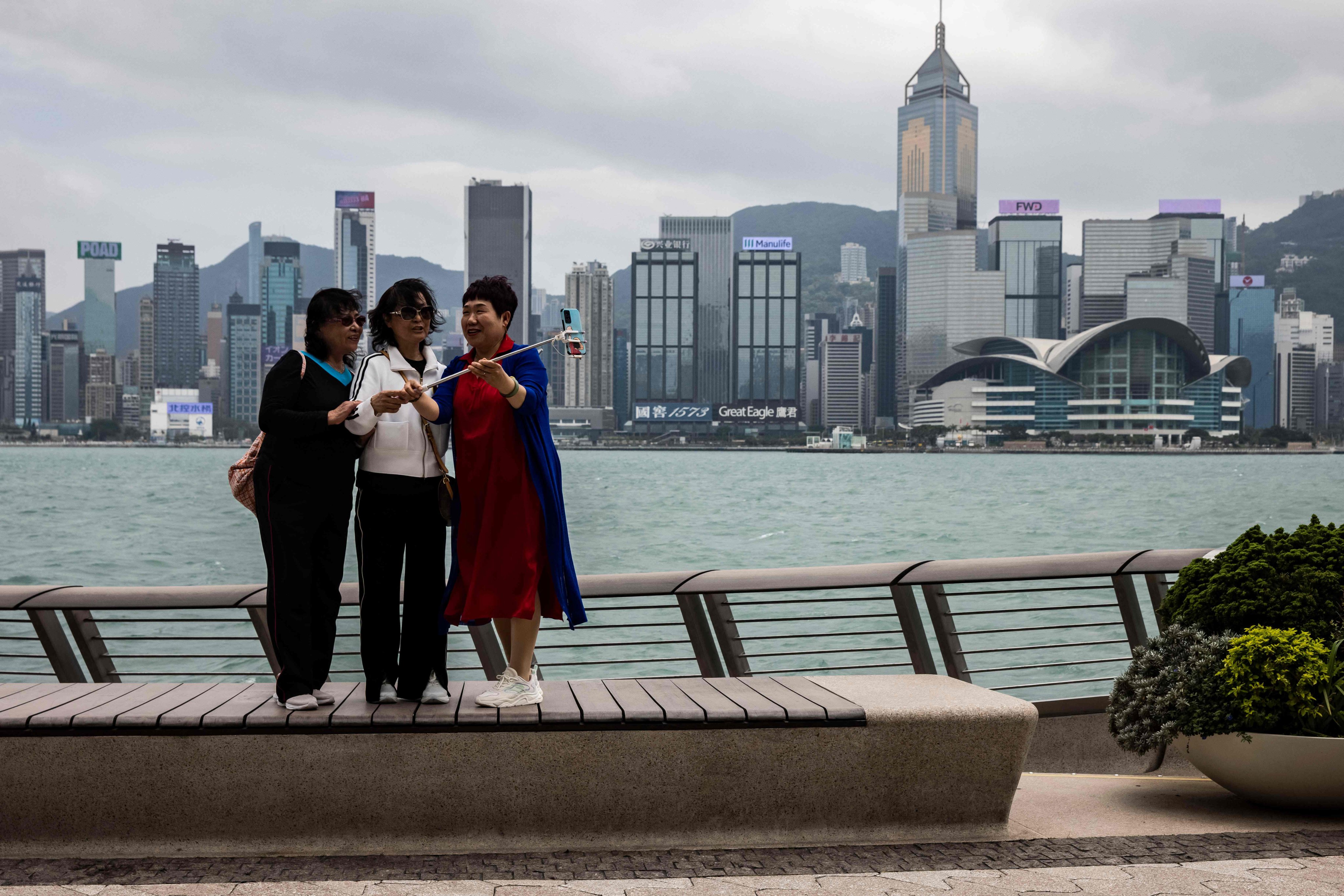 Mainland tourists take pictures along the promenade next to Victoria Harbour in Hong Kong on May 11. While the mainland is developing in high speed, Hong Kong is seriously lagging behind. Photo: AFP 