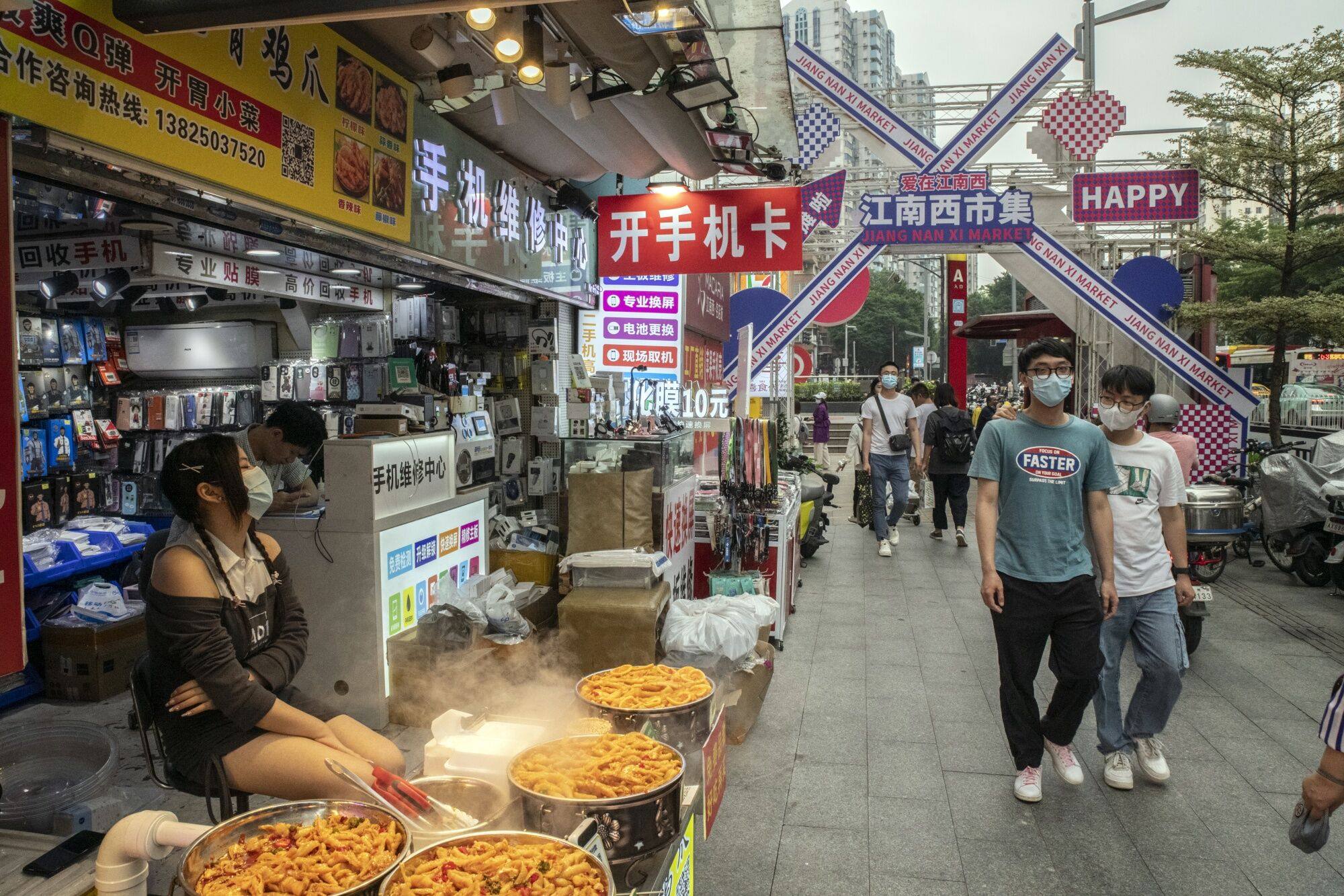 Pedestrians pass stores in the Haizhu area of Guangzhou on May 9, 2023. Photo: Bloomberg