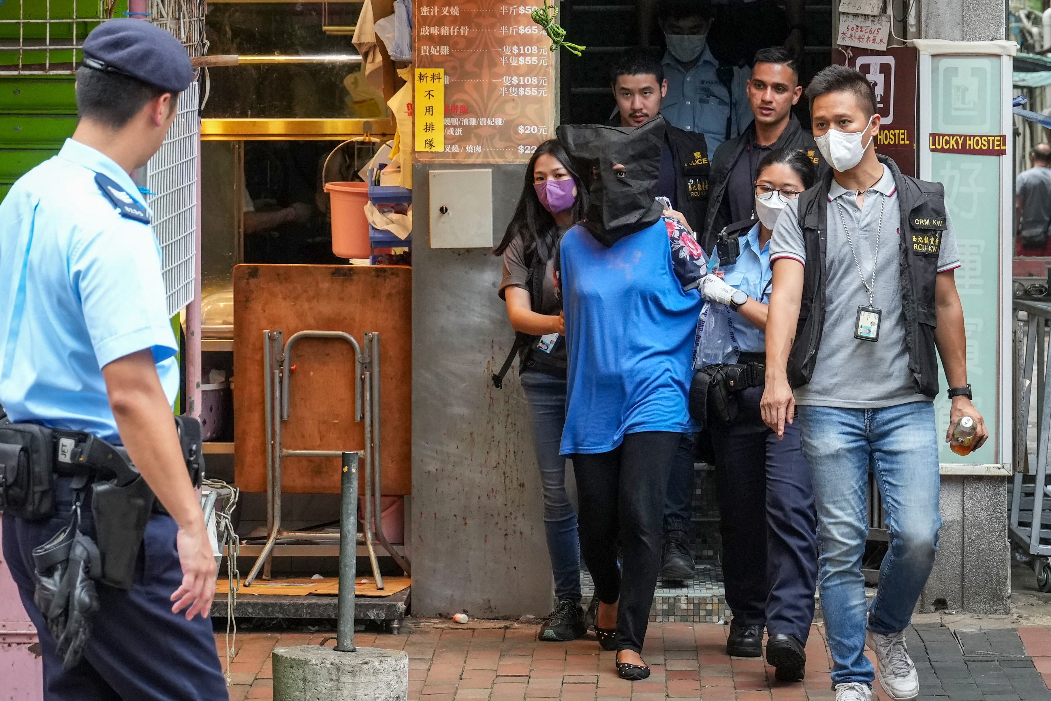 Police escort a woman suspected of killing her three children from her flat in Sham Shui Po. Photo: Sam Tsang