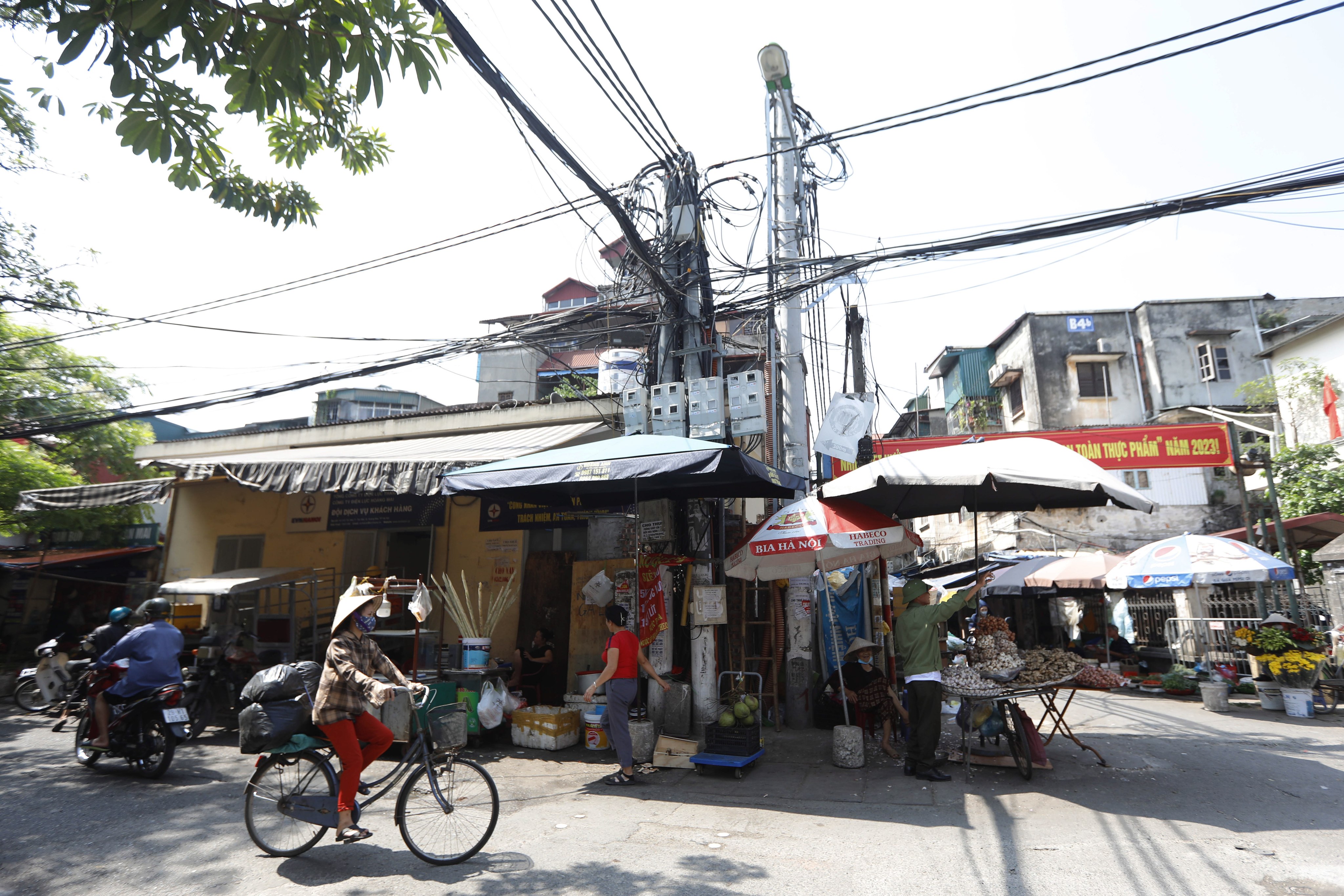 A woman rides a bicycle past utility poles with power cables in a street in Hanoi.  Photo: EPA-EFE