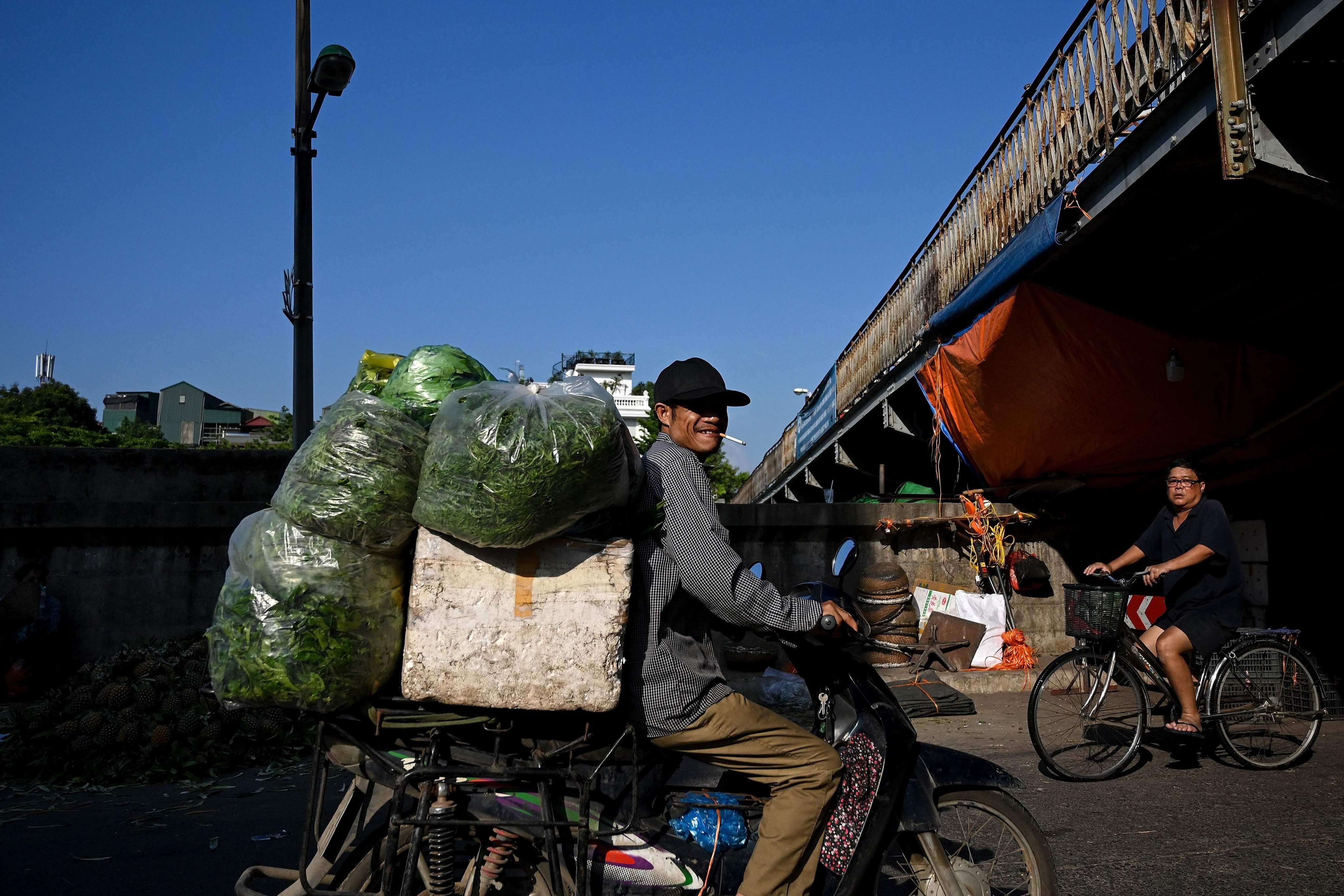 A vendor smokes a cigarette while carrying vegetables in Hanoi. Photo: AFP 