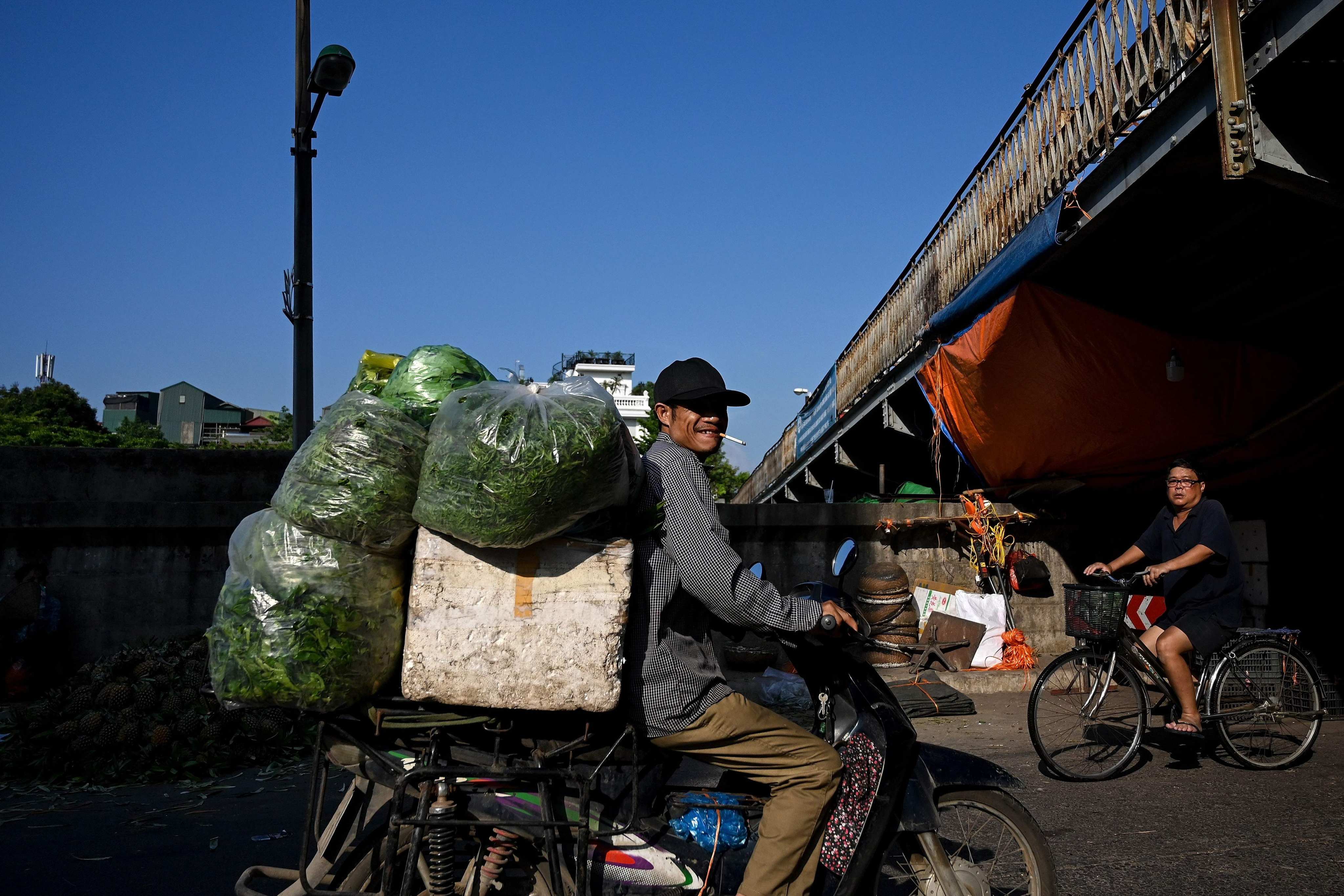 A vendor smokes a cigarette while carrying vegetables in Hanoi. Photo: AFP
