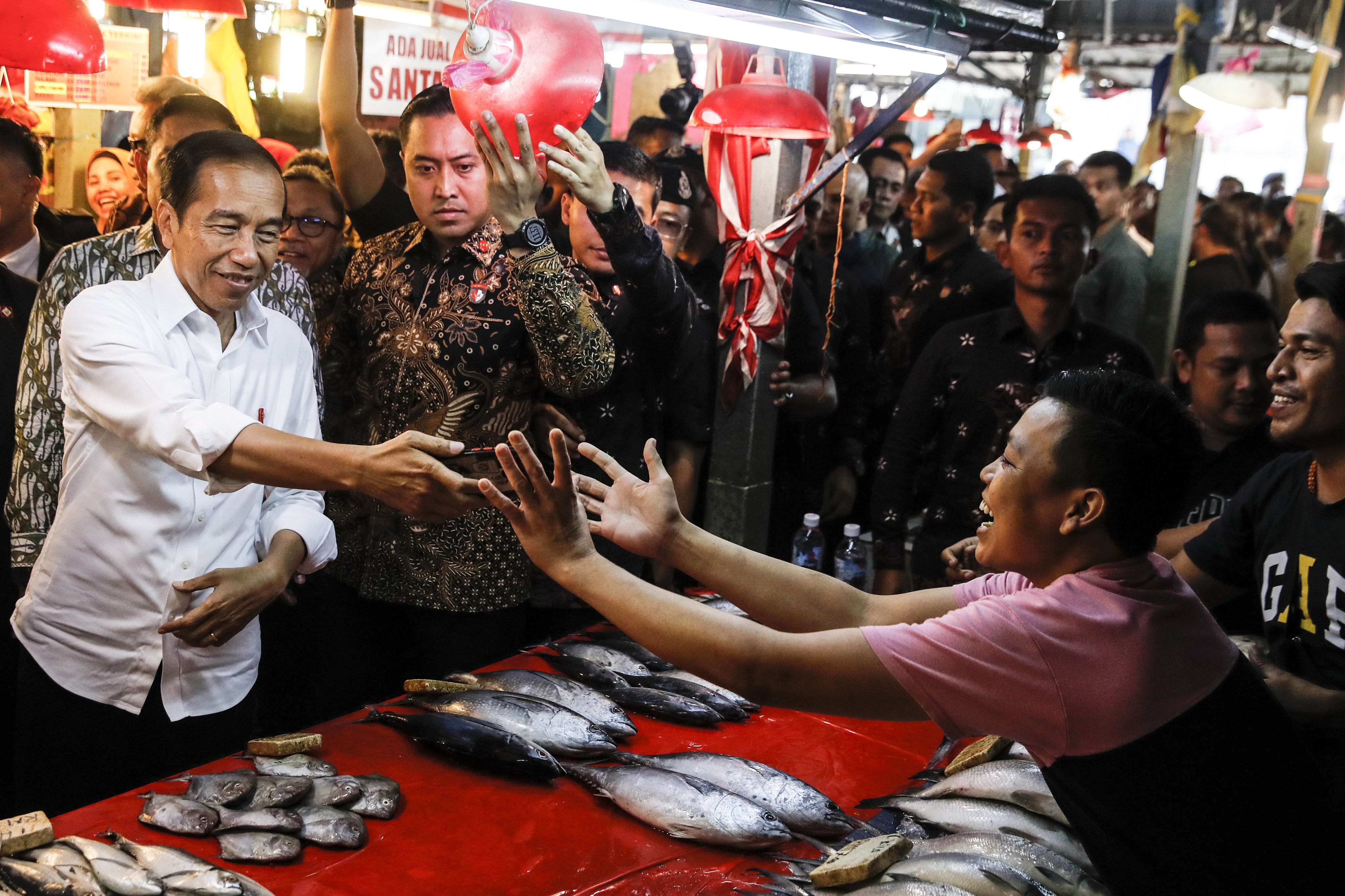 President Joko Widodo (left) hands over a mobile phone after taking a selfie with an Indonesian worker during his visit to the Chow Kit wet market in Kuala Lumpur on Thursday. Photo: EPA-EFE

