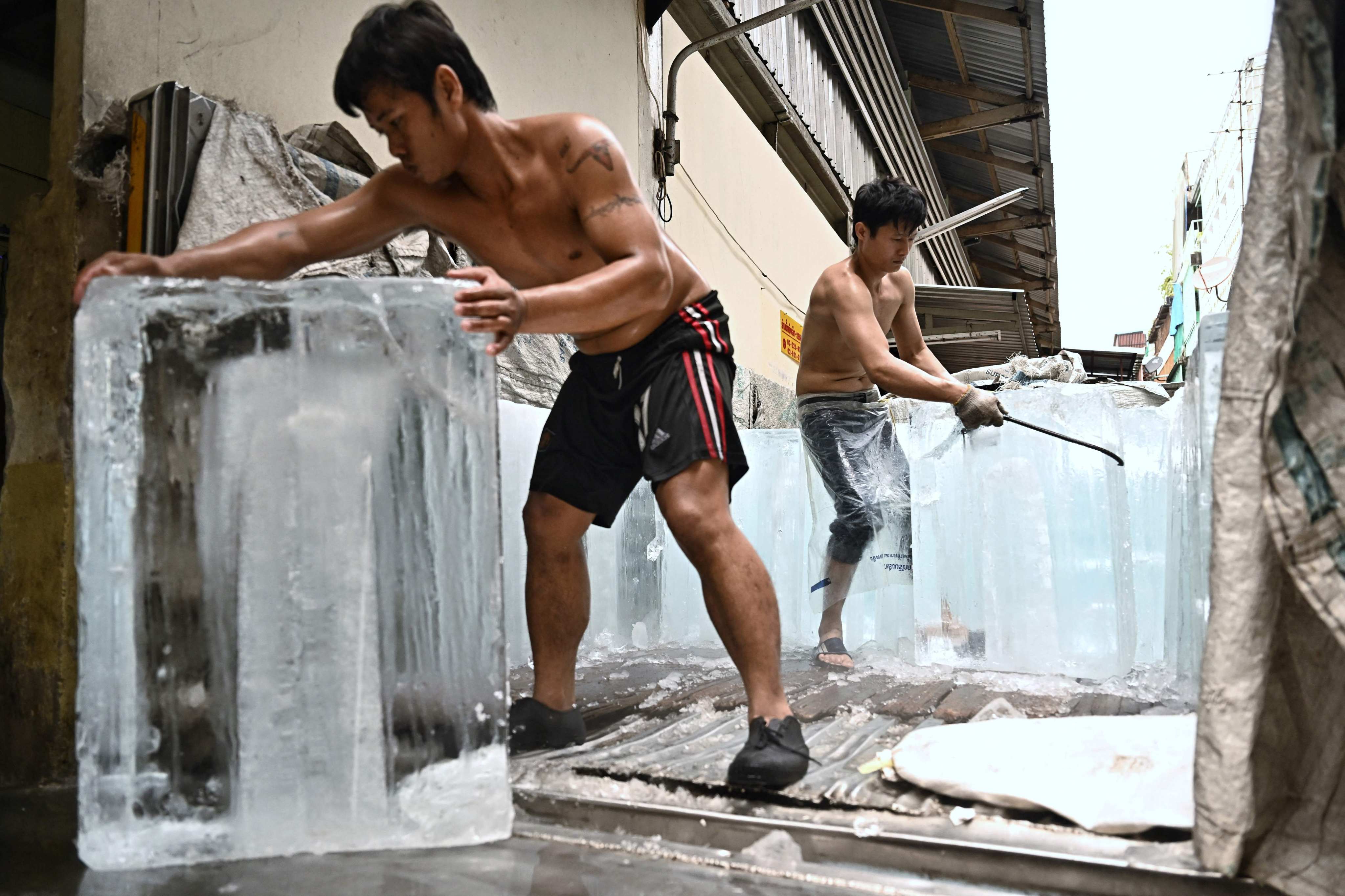 Workers move blocks of ice into a storage unit at a market during a heatwave in Bangkok on April 25. Scientists say global warming is exacerbating adverse weather, with many countries experiencing deadly heatwaves and temperatures hitting records across Southeast and South Asia in recent weeks. Photo: AFP