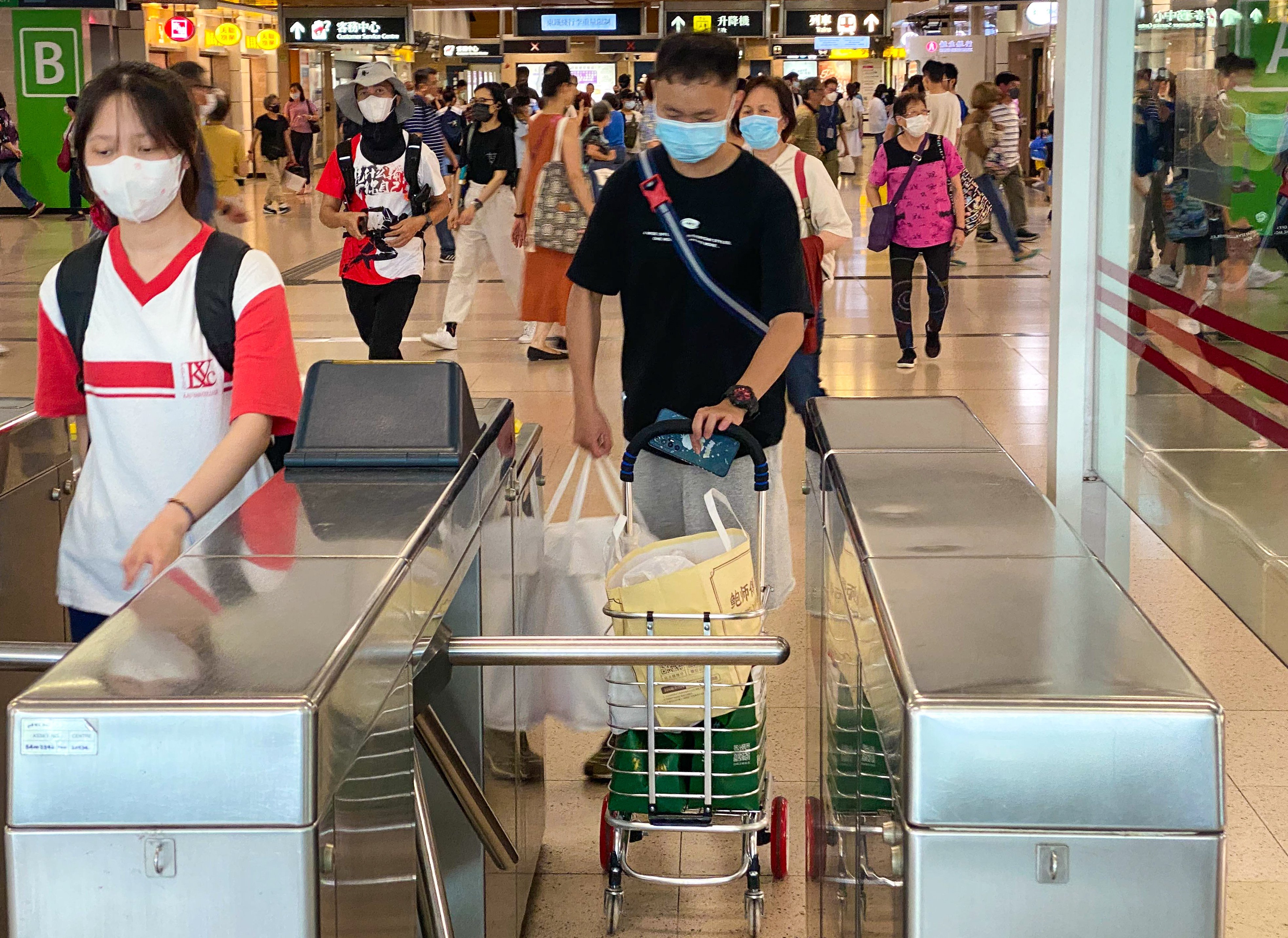 “Daigou” courier Ye Qingren (centre) passes through an MTR station on the way to meeting one of his customers. Photo: Fiona Sun