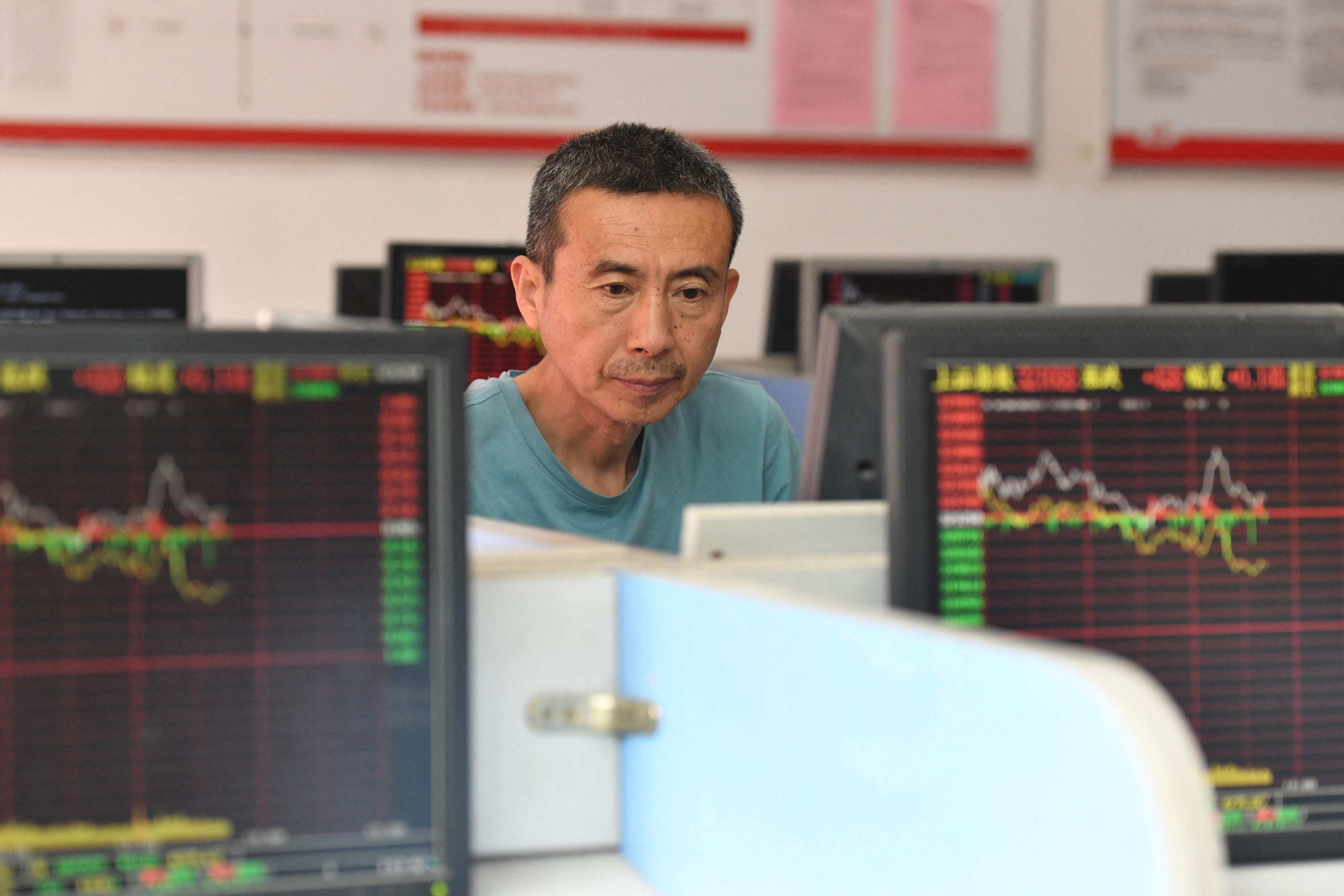 An investor looks at screens showing stock market movements at a securities company in Fuyang, Anhui province, on May 29. With the property market in distress, Chinese money is stuck in bank deposits, instead of finding its way into the real economy. Beijing could consider redirecting household wealth from property to the equity market. Photo: AFP 