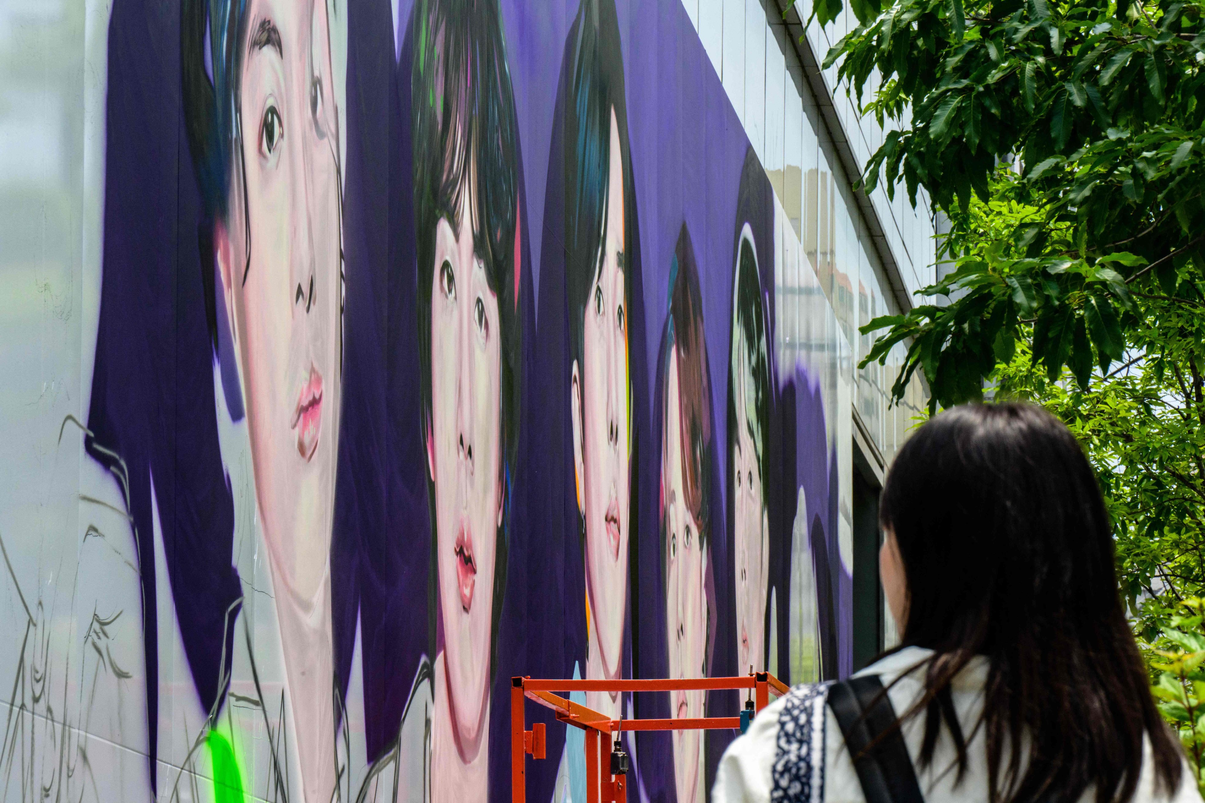 A woman looks at an in-progress mural of K-pop megastars BTS in Seoul. Photo: AFP