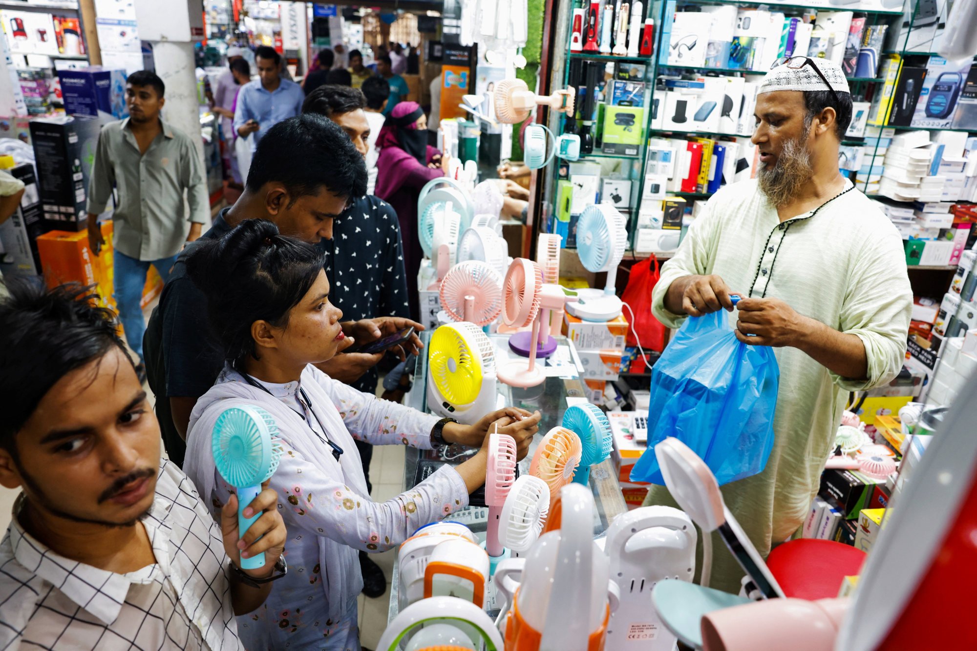People gather at an electronics shop in Dhaka to buy fans during a countrywide heatwave earlier this month. The average Bangladeshi is 157.29cm tall. Photo: Reuters