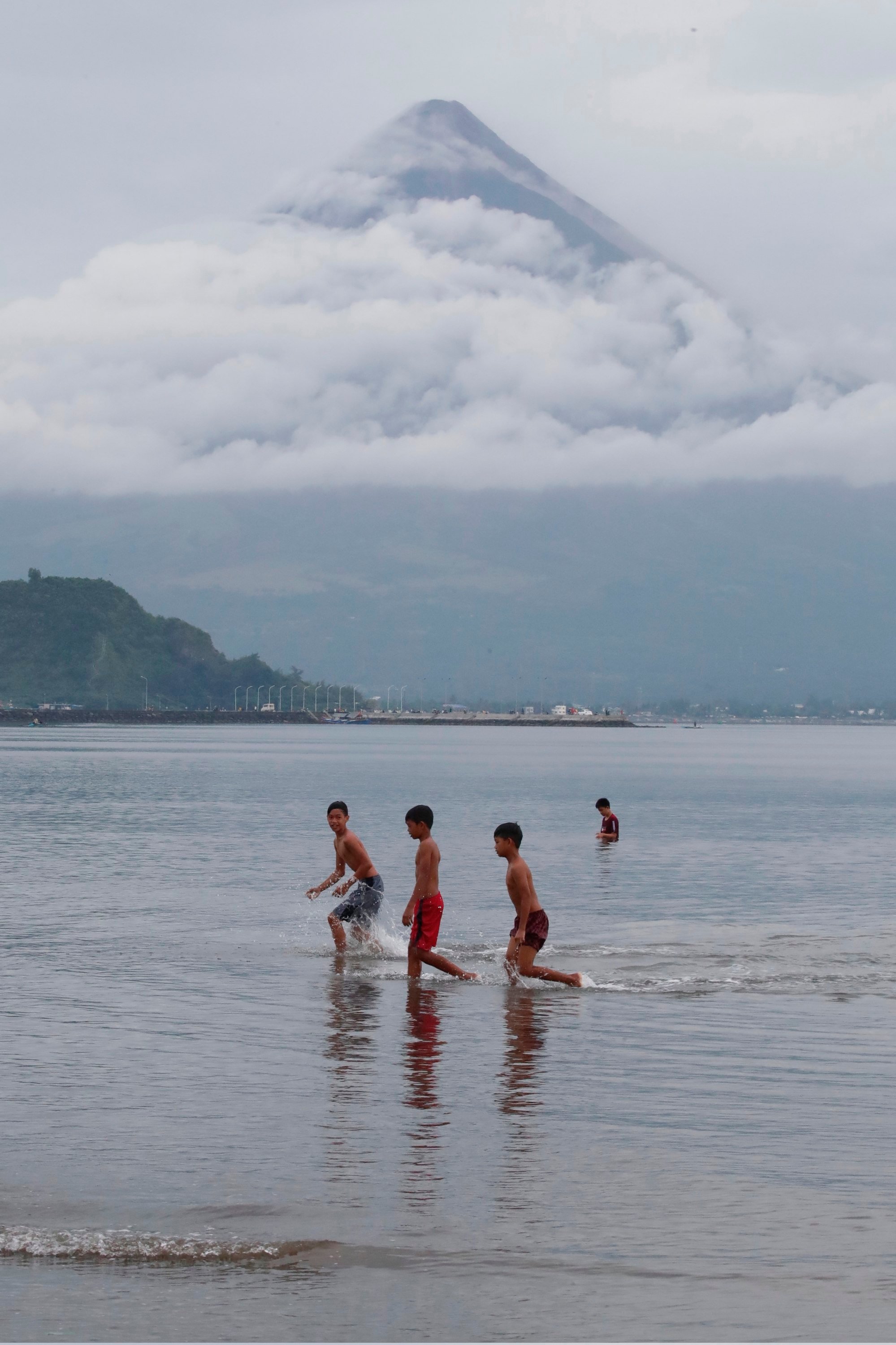 Filipino children frolic in a lake in Philippines’ Albay province with the active Mayon volcano in the background. The average Filipino is 156.41cm tall. Photo: EPA-EFE