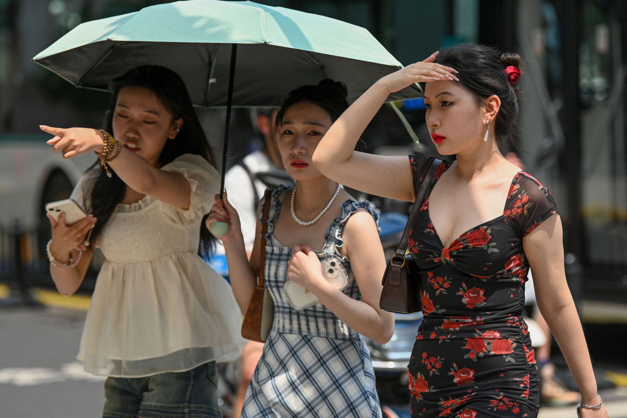 Women use an umbrella to shelter from the sun on a hot day in Shanghai on May 29, 2023. Photo: AFP