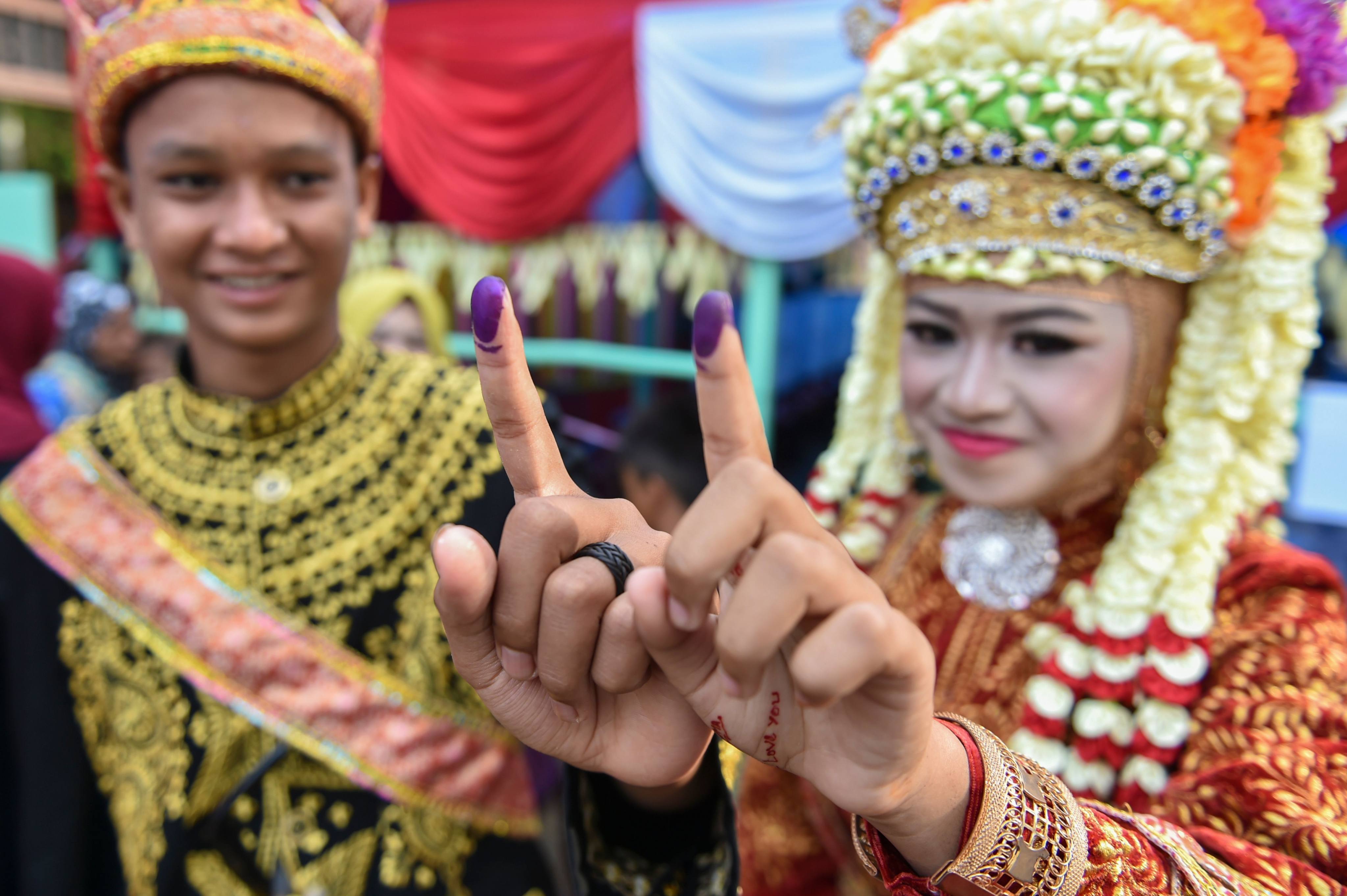 Indonesians show their inked fingers after voting on April 17, 2019. Indonesia’s current open list proportional voting system means that voters can cast ballots for either an individual candidate or a party. Photo: AFP