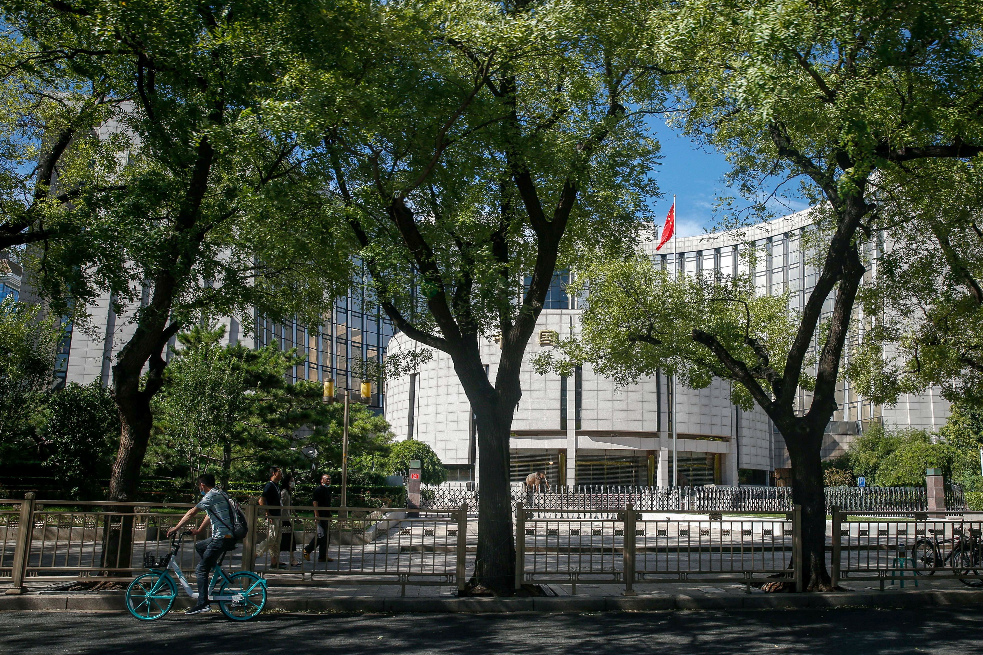 A man rides a bicycle outside the People’s Bank of China headquarters in Beijing in August 2022. Photo: EPA-EFE