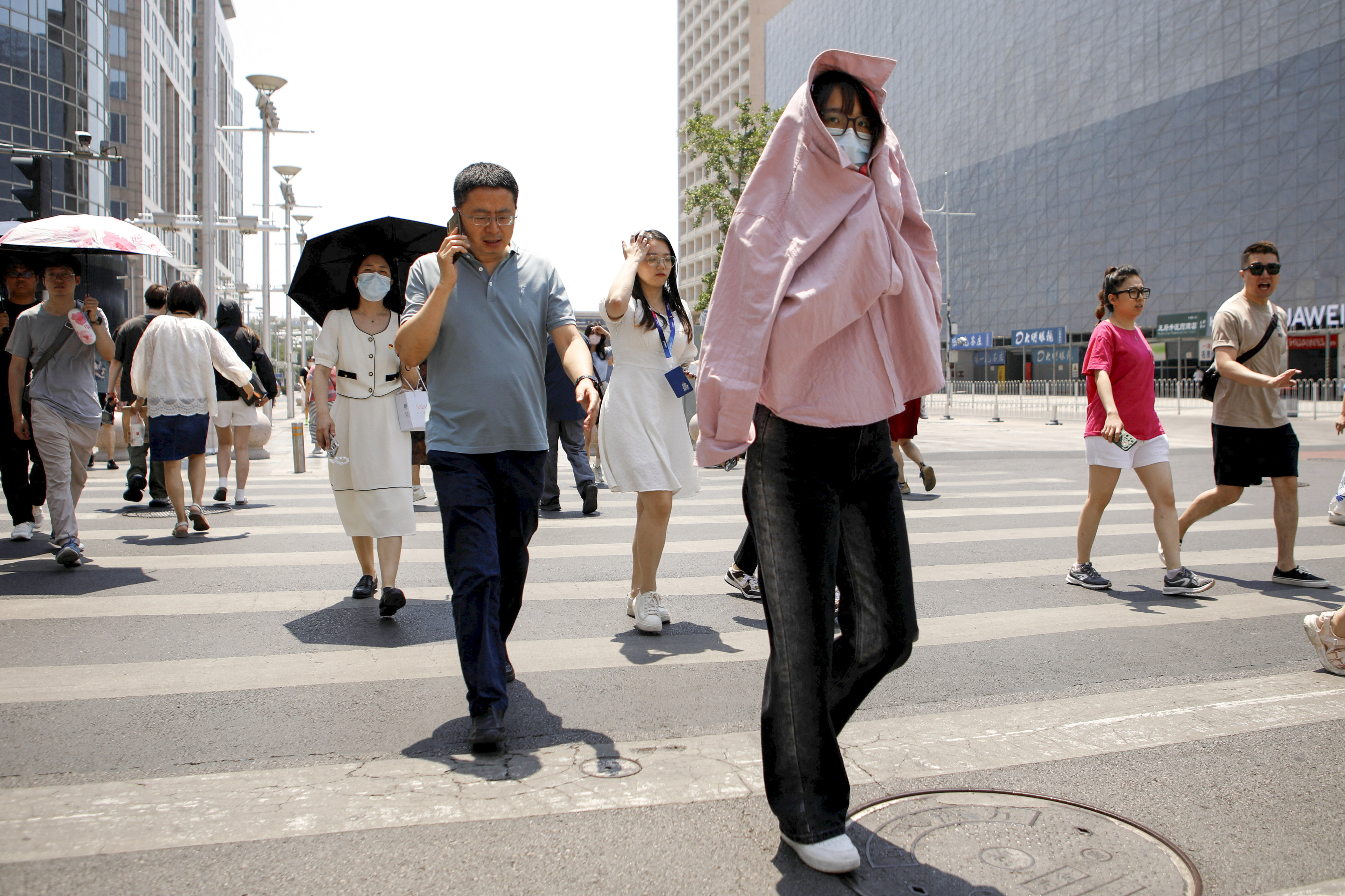 A pedestrian shields herself from the sun amid an orange heatwave alert in Beijing on Friday. Photo: Reuters