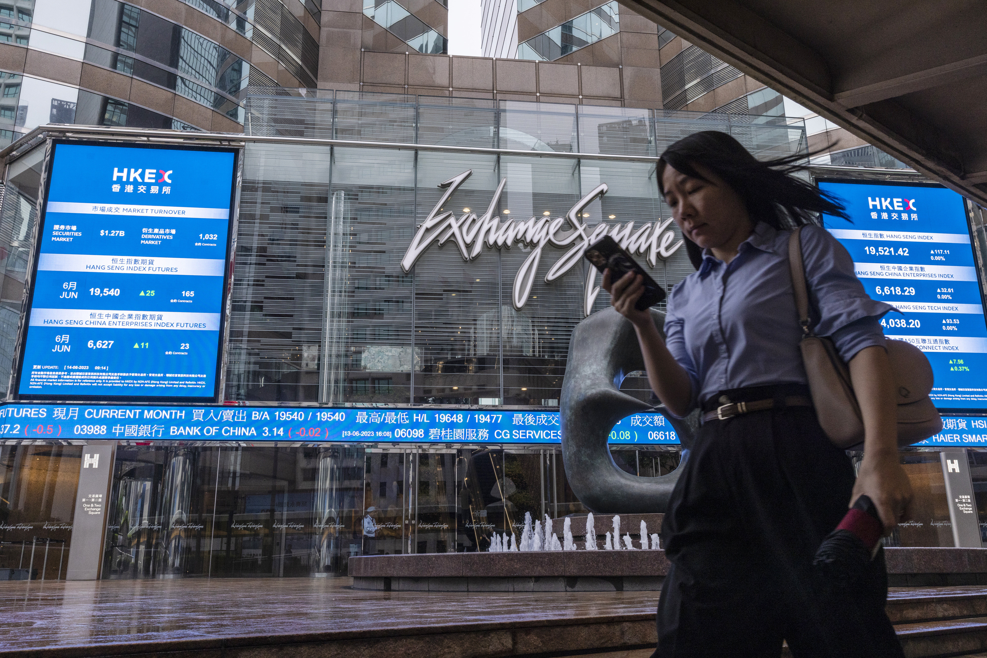 A pedestrian passes by the Hong Kong Stock Exchange electronic screen in Hong Kong, Photo: AP